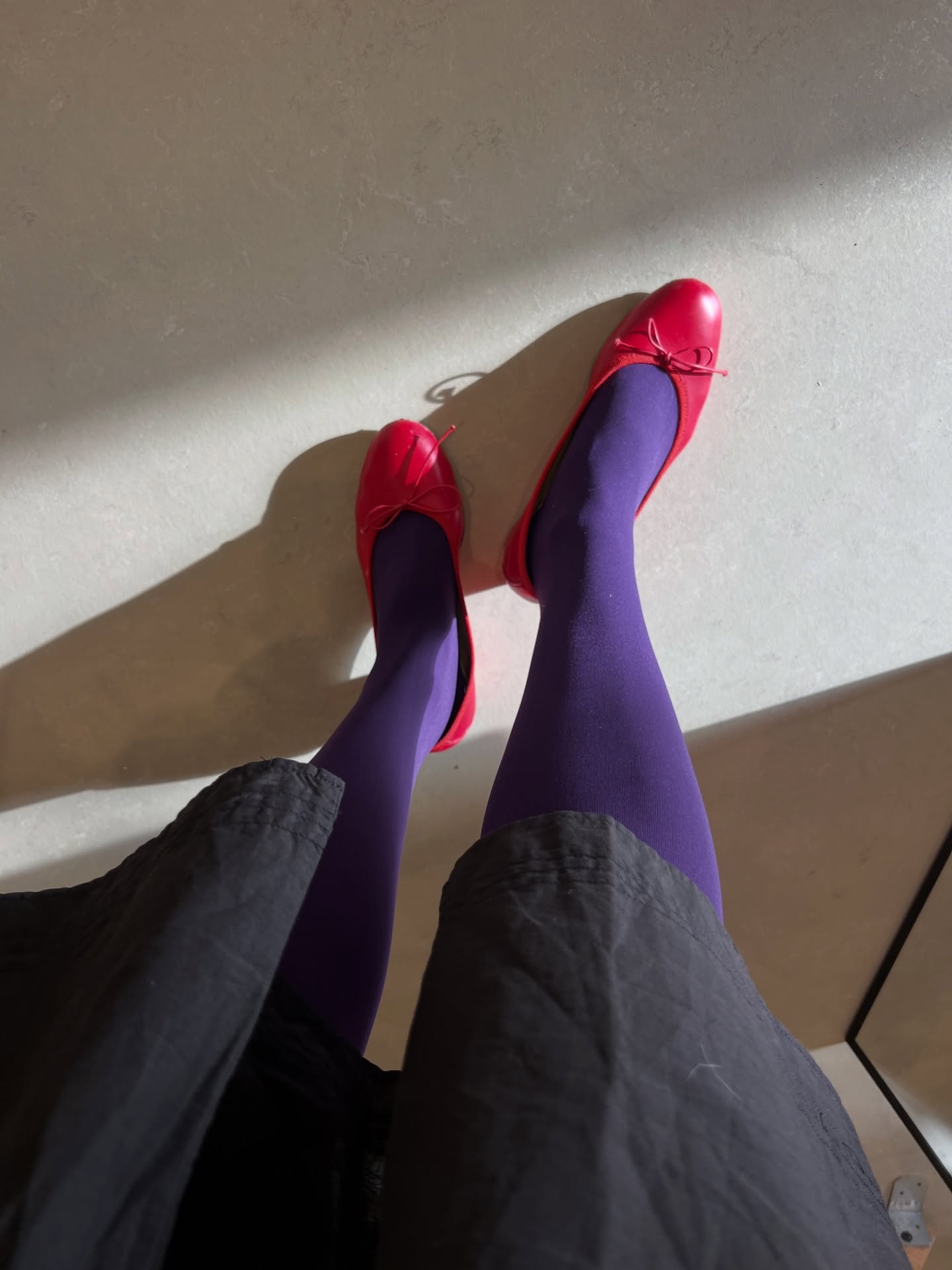 Influencer @vivianyrl wears royal purple tights with red ballet flats and a grey skirt.