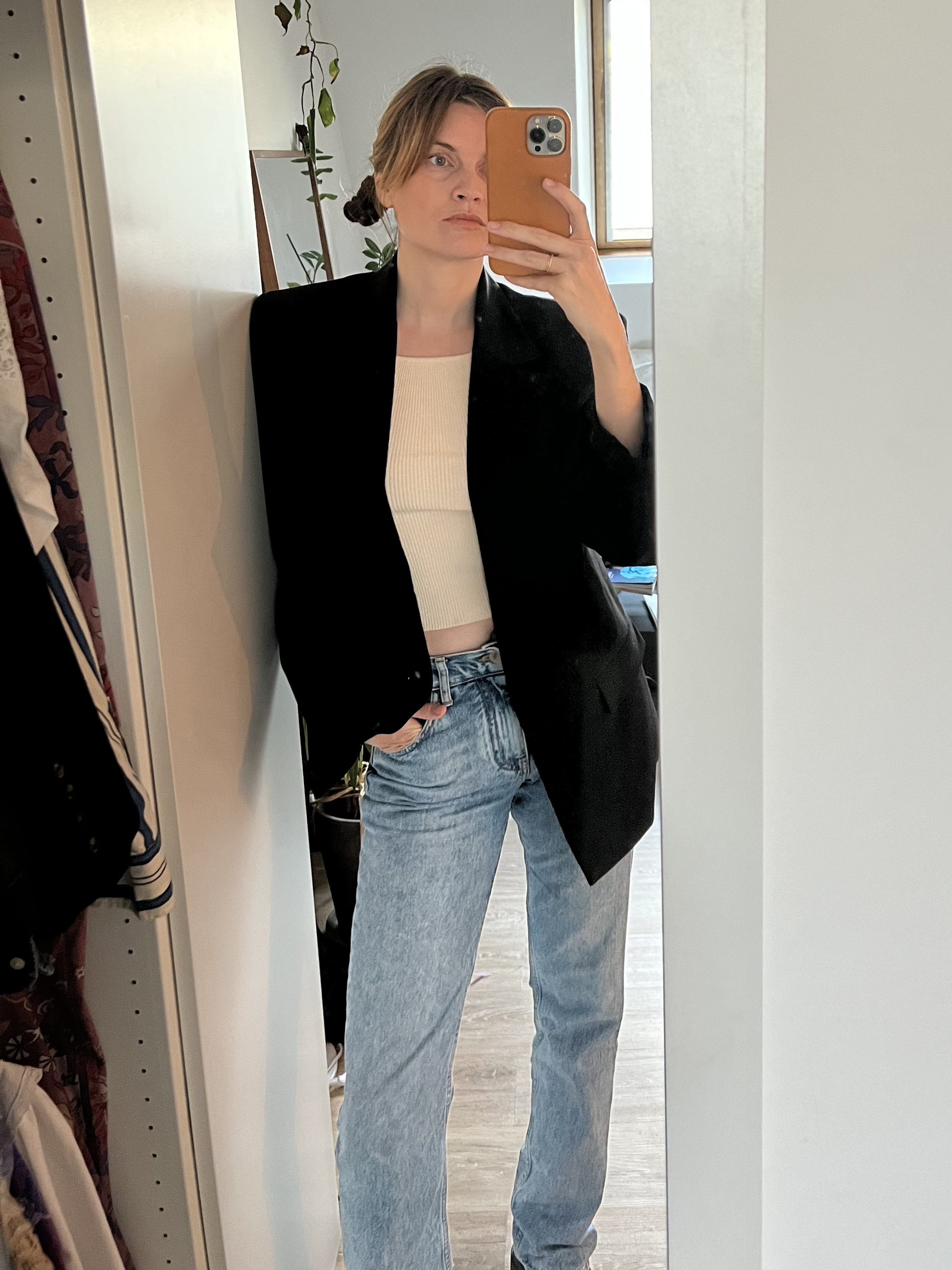 French writer and editor Eugenie Trochu poses for a mirror selfie wearing a black blazer, white T-shirt, and straight-leg jeans