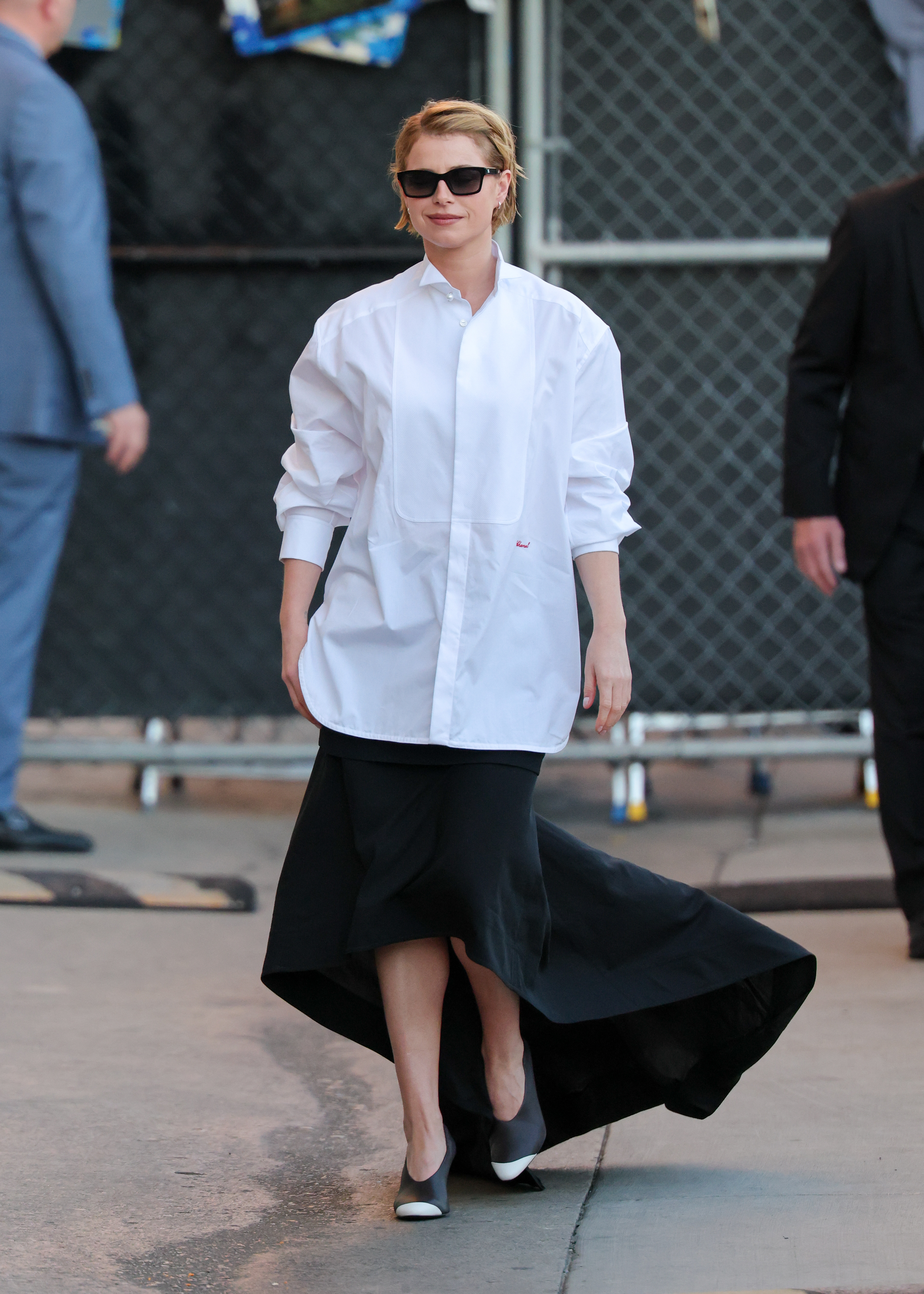Jessie Buckley wears a white skirt with a black skirt and dipped toe heels.