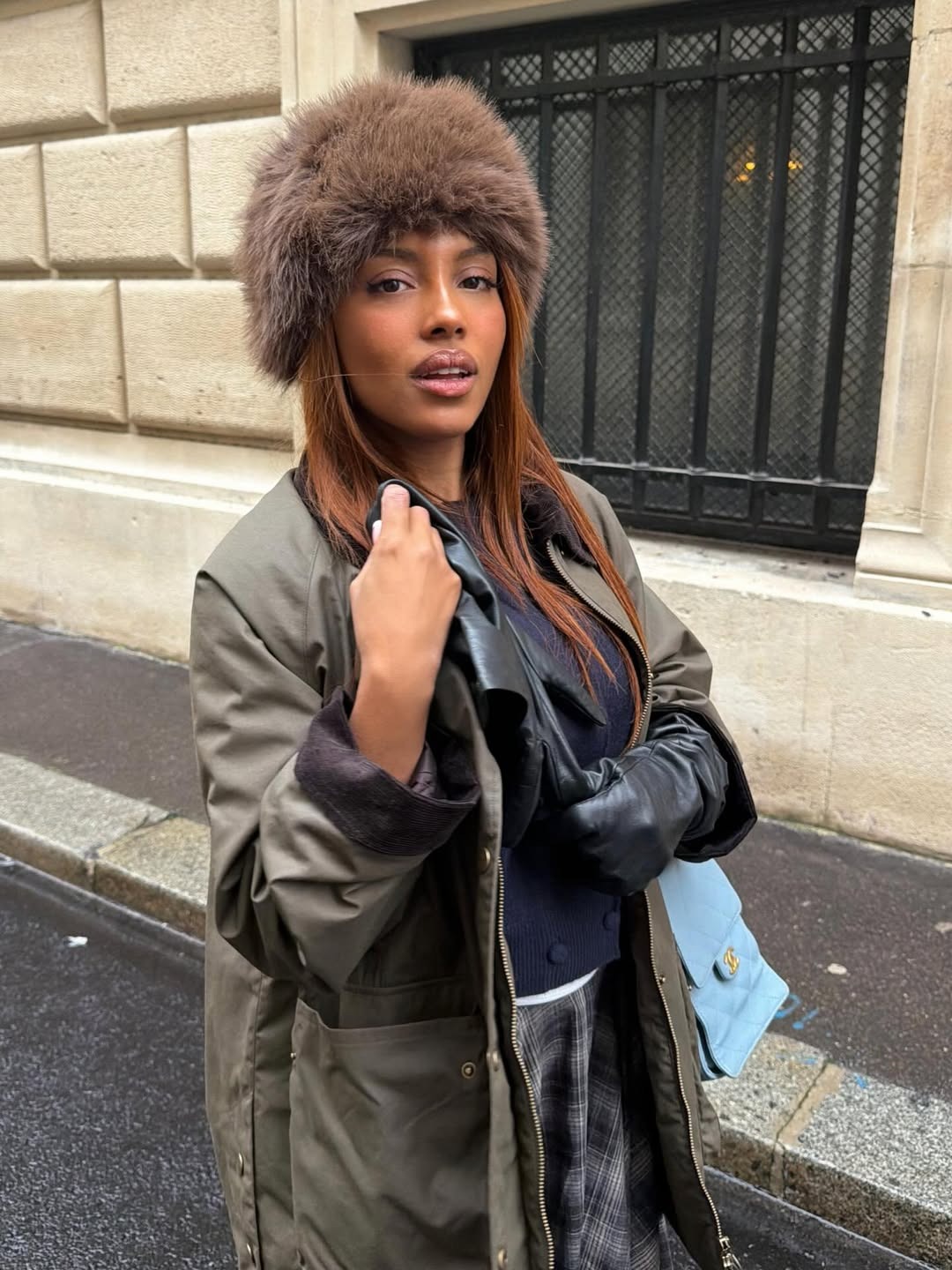 @mv.tiangue wears a plaid skirt, barn coat, leather gloves, and a fur hat.