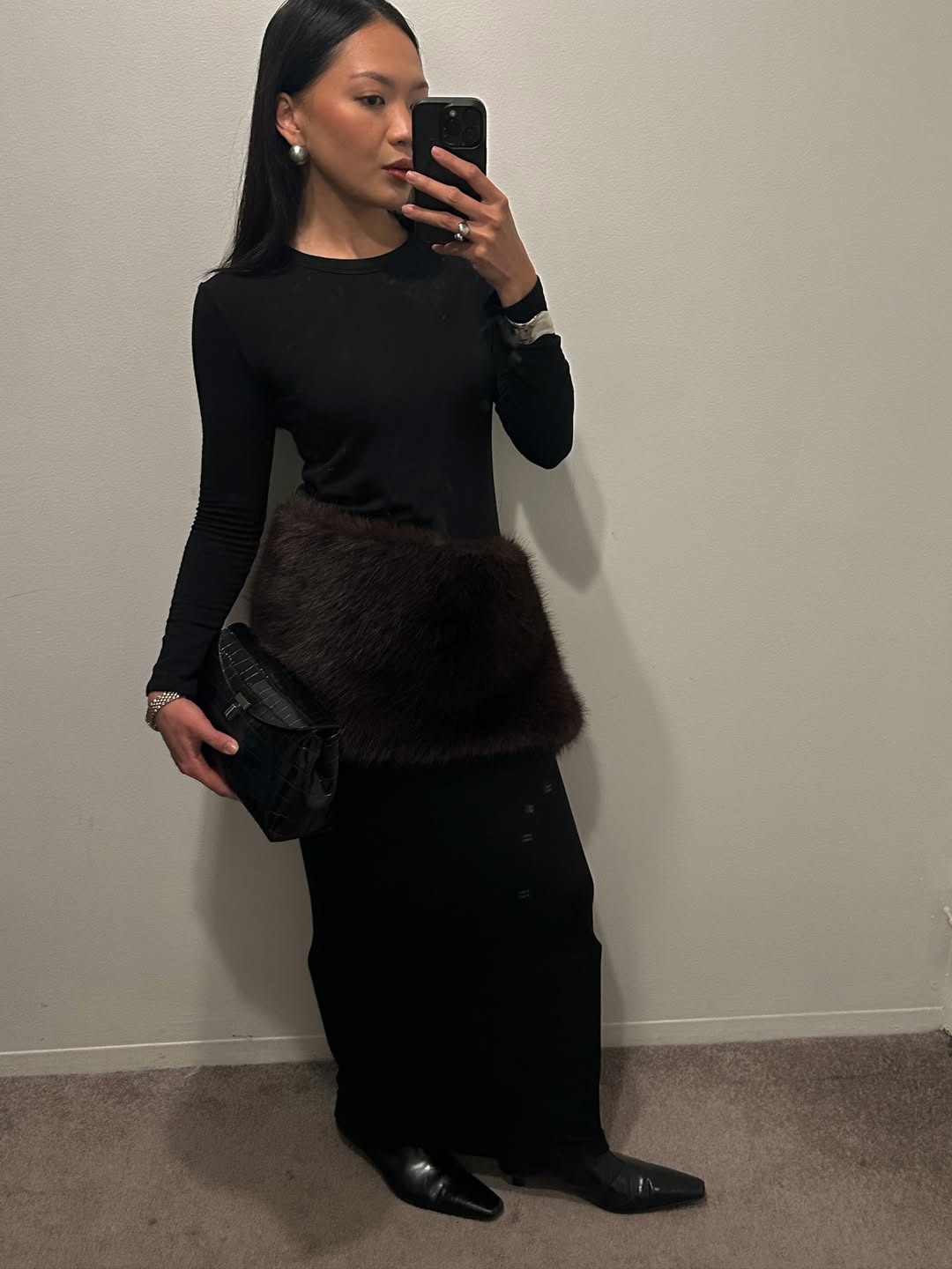 @dawn.tan wears a black maxi skirt, long sleeves, and a brown fur scarf tied around her waist.