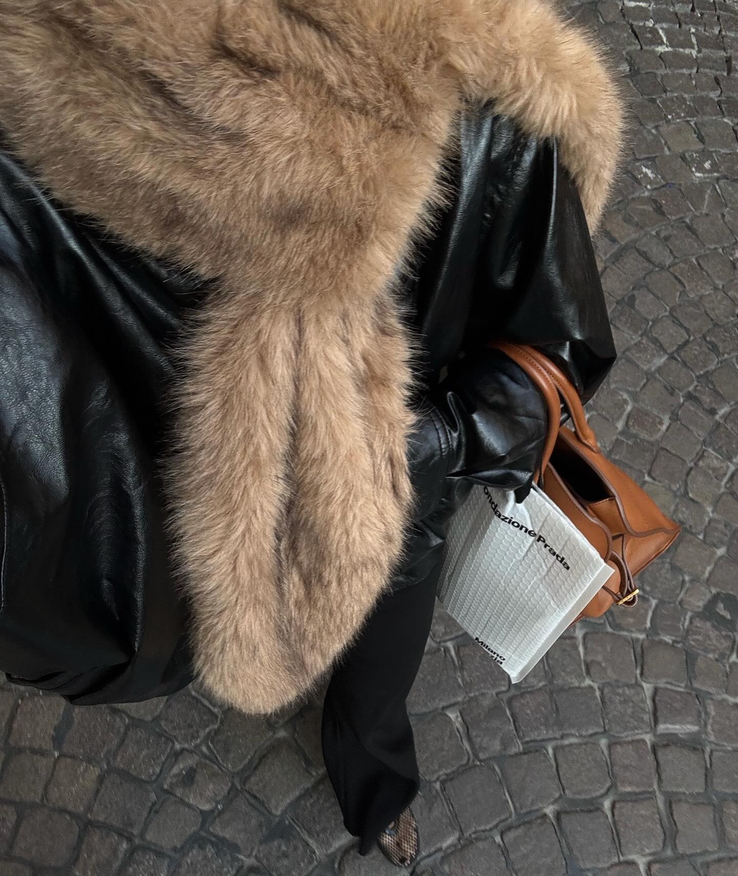 @rikkekrefting in a black leather jacket, a fur scarf, and a colored bag.