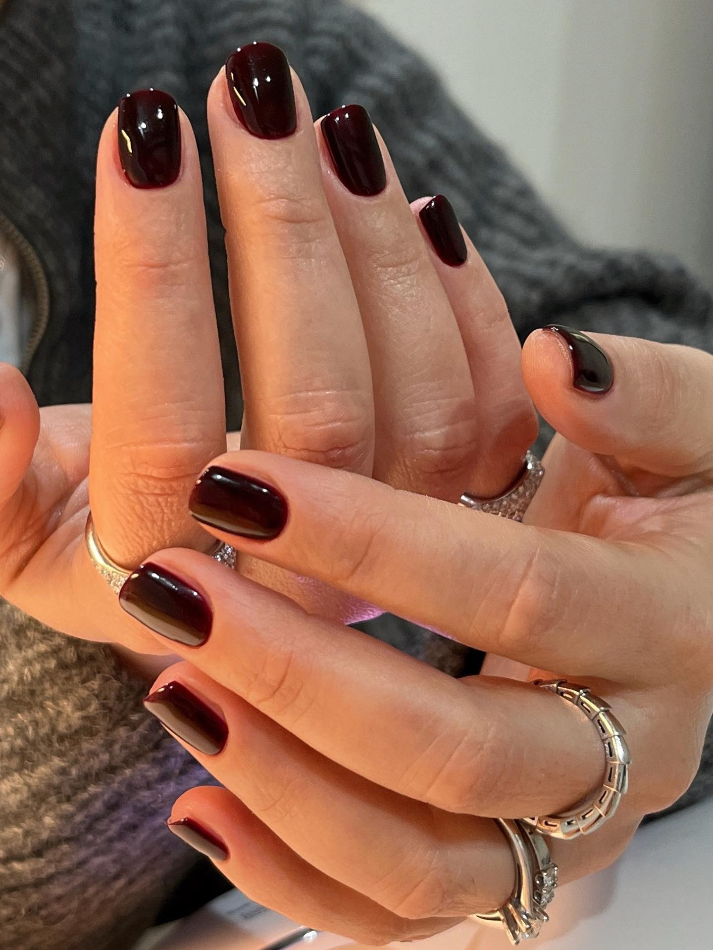 A woman with a short, square, maroon manicure