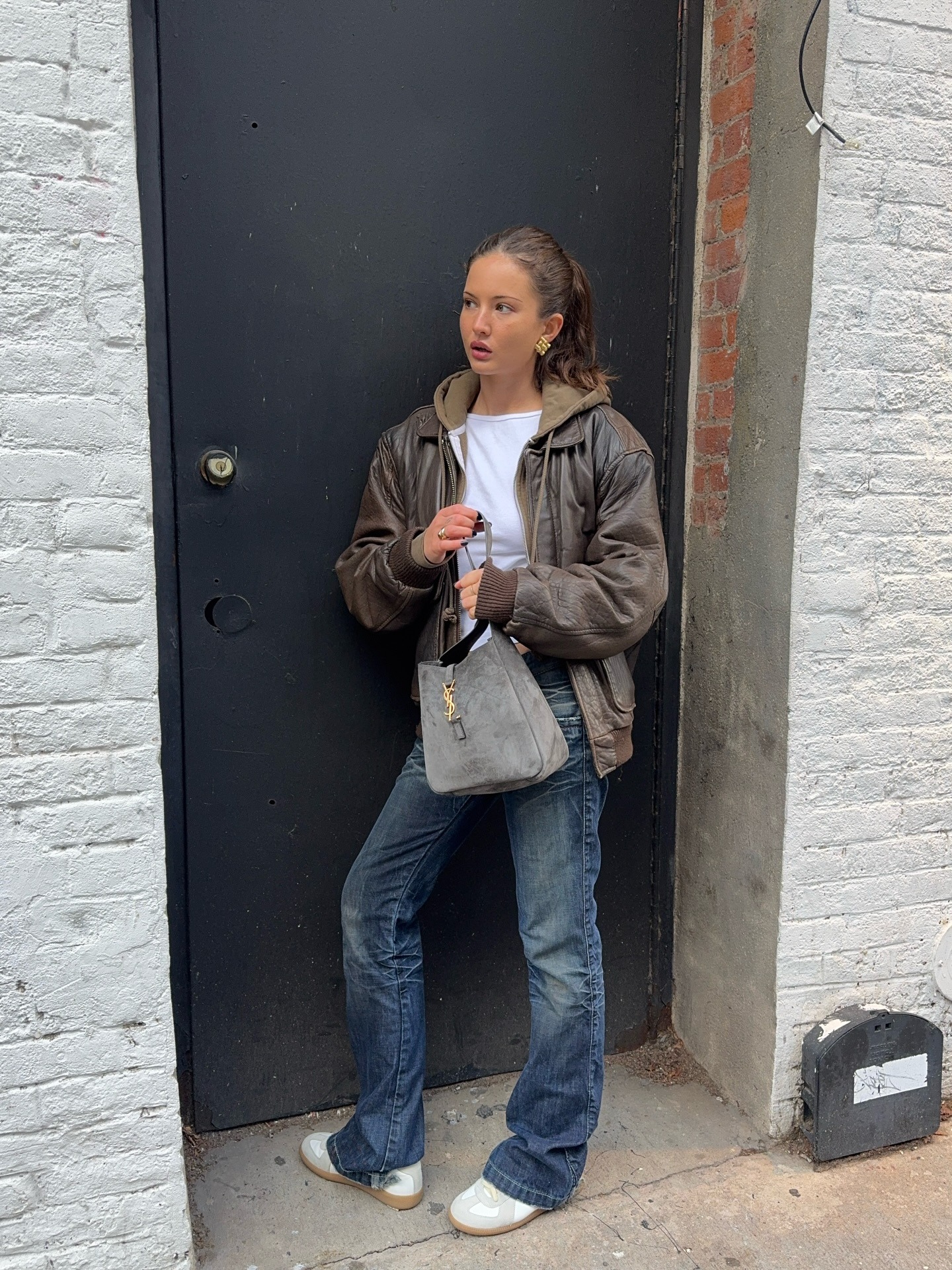 @rubylyn_ wears a white tee, hoodie, leather jacket, sneakers, and bootcut jeans.