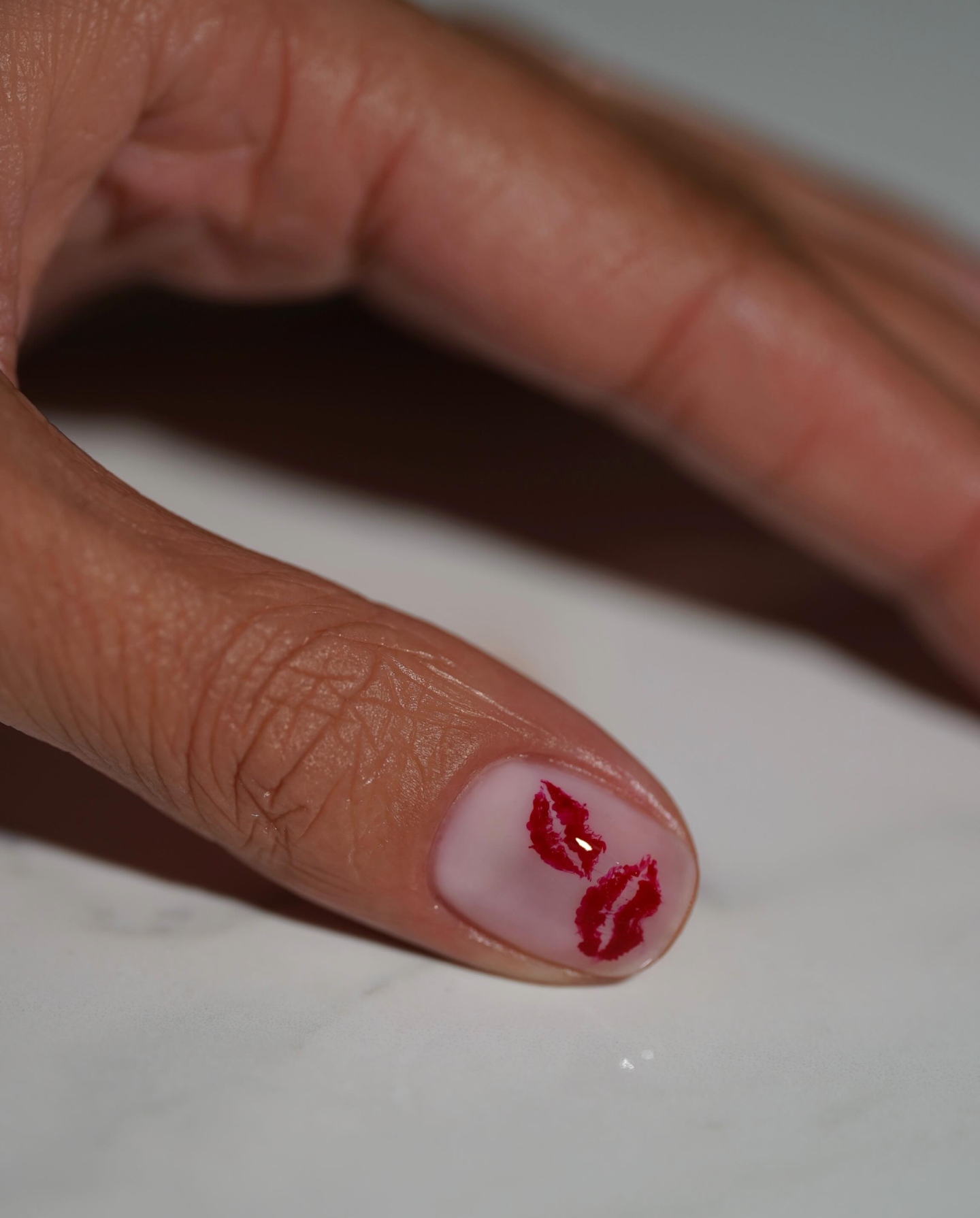 A manicure with a red lipstick print by Iram Shelton