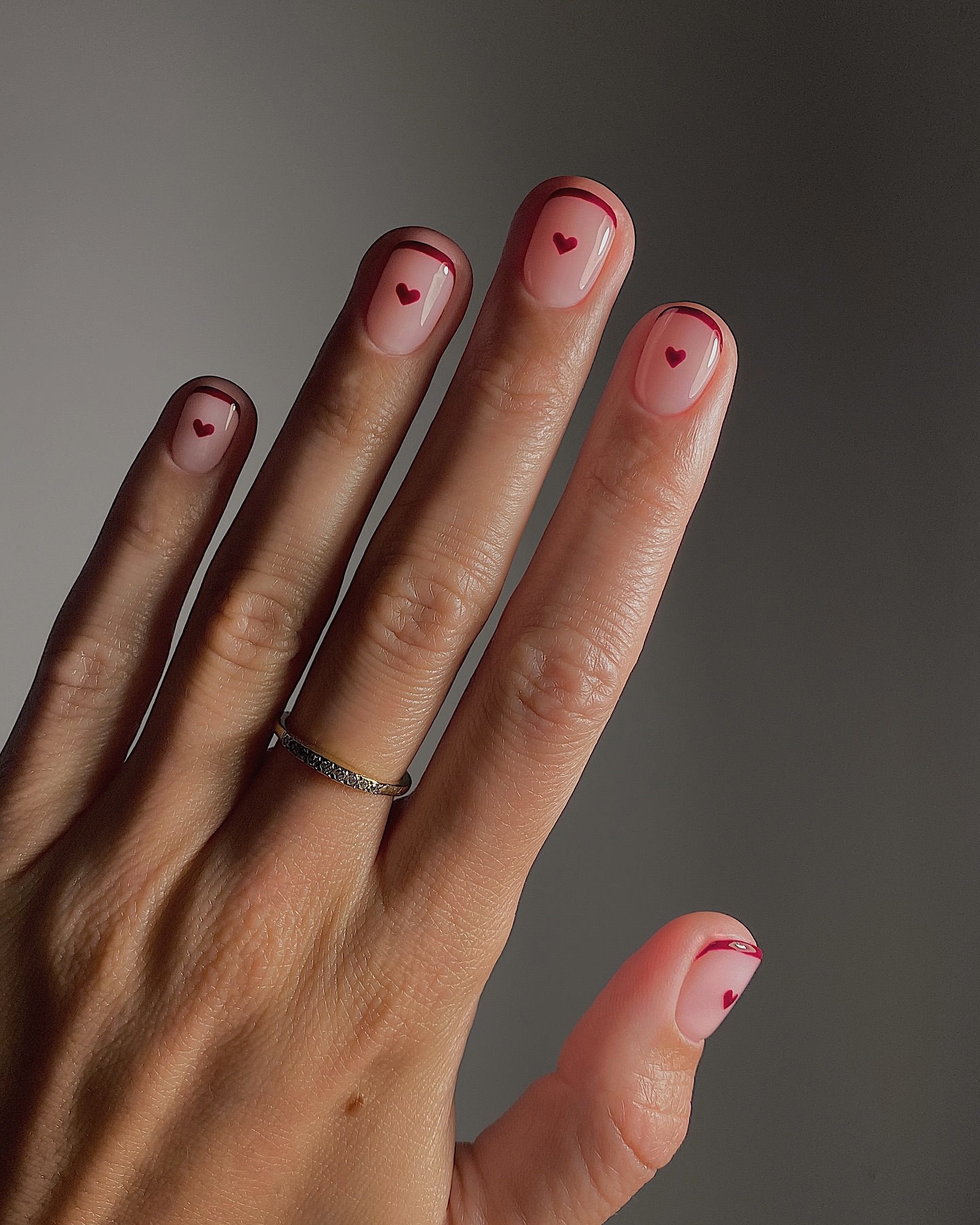 A manicured with red French tips and small heart nail art by Mateja Novakovic