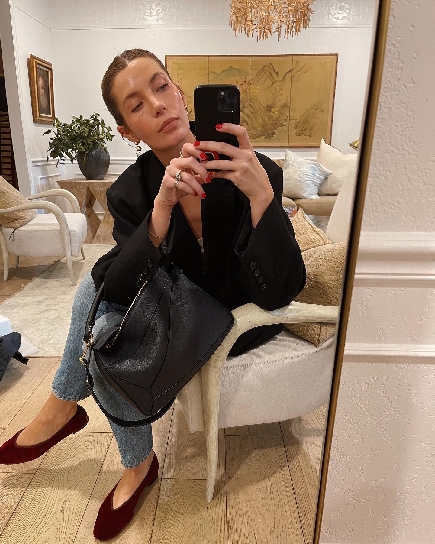 Style influencer Courtney Grow poses for a mirror selfie wearing a black blazer jacket, Loewe Puzzle bag, slim straight-leg, and burgundy v-cut flats