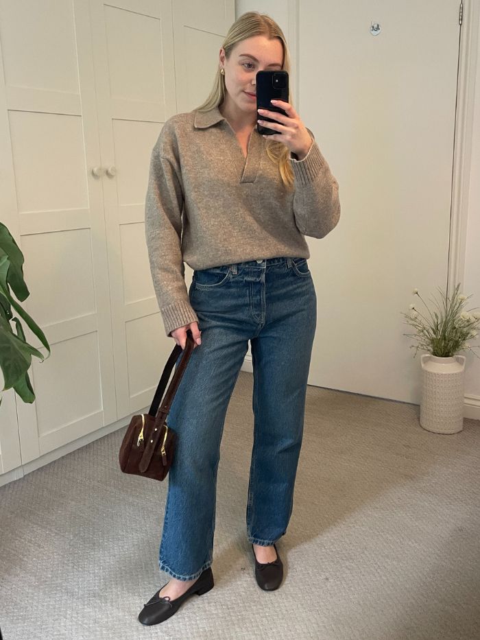 Woman wears beige polo jumper, blue jeans and ballet flats