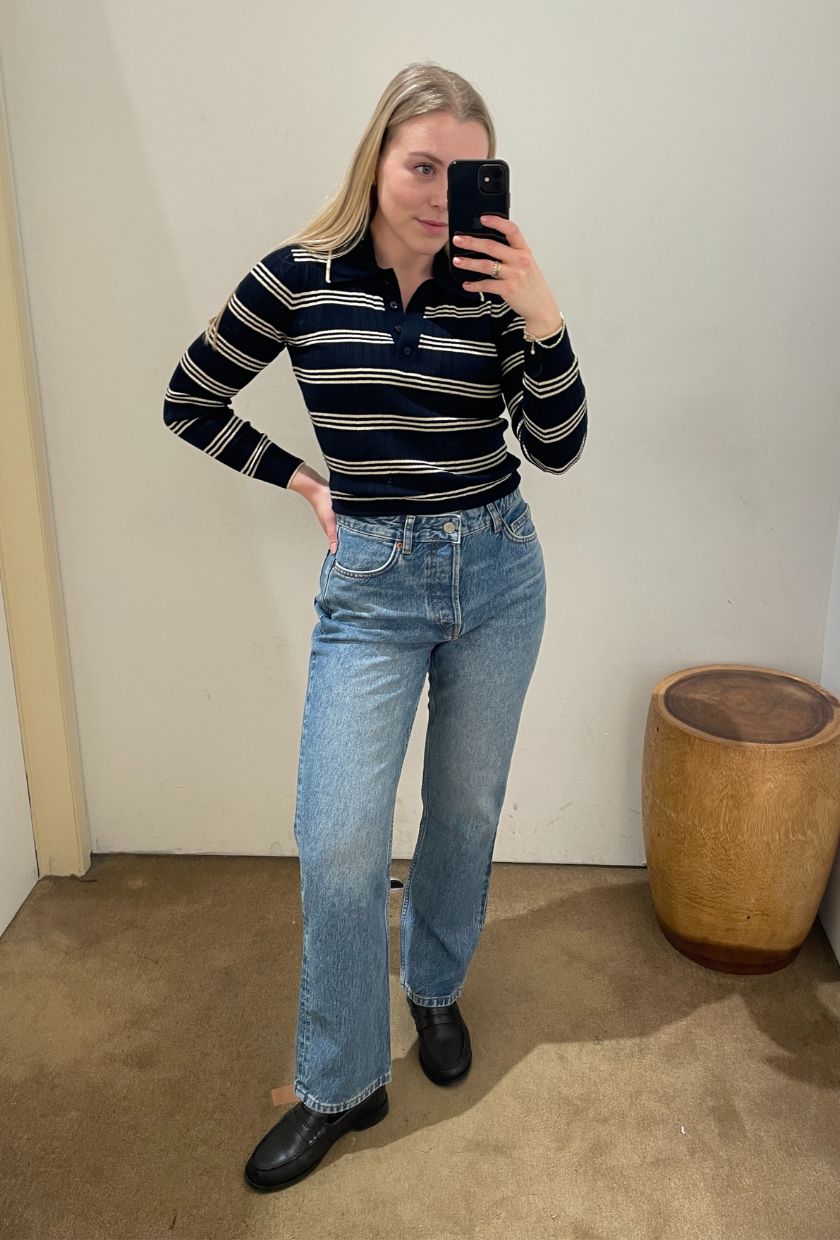 Florrie wears a navy striped sweater from Reformation, blue straight-leg jeans and black loafers