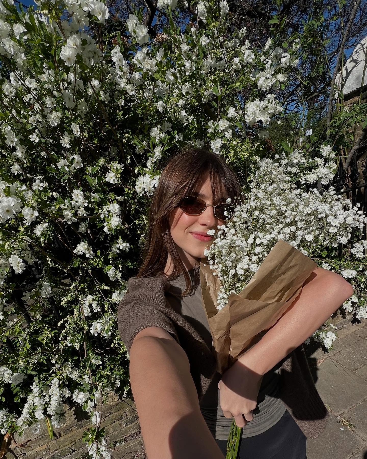 Daisy Edgar Jones taking a selfie holding a bunch of flowers with a wispy fringe hairstyle