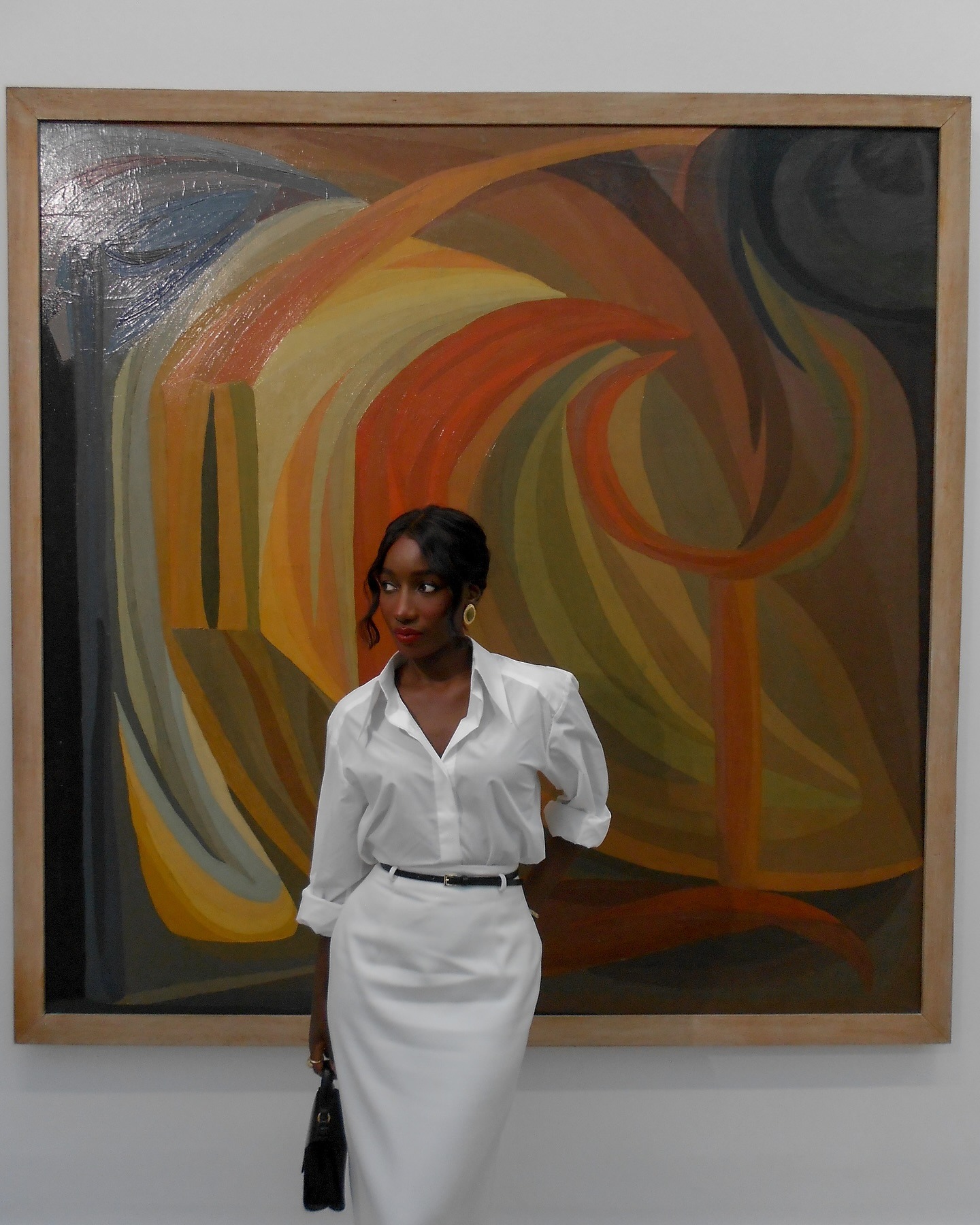 Aida wears a white button-down shirt with a white pencil skirt.