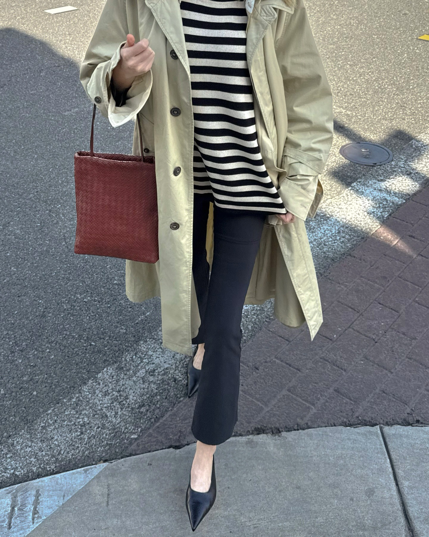 Elsa Hosk wearing a trench coat, striped shirt, cropped flare pants, and kitten-heel slingback shoes