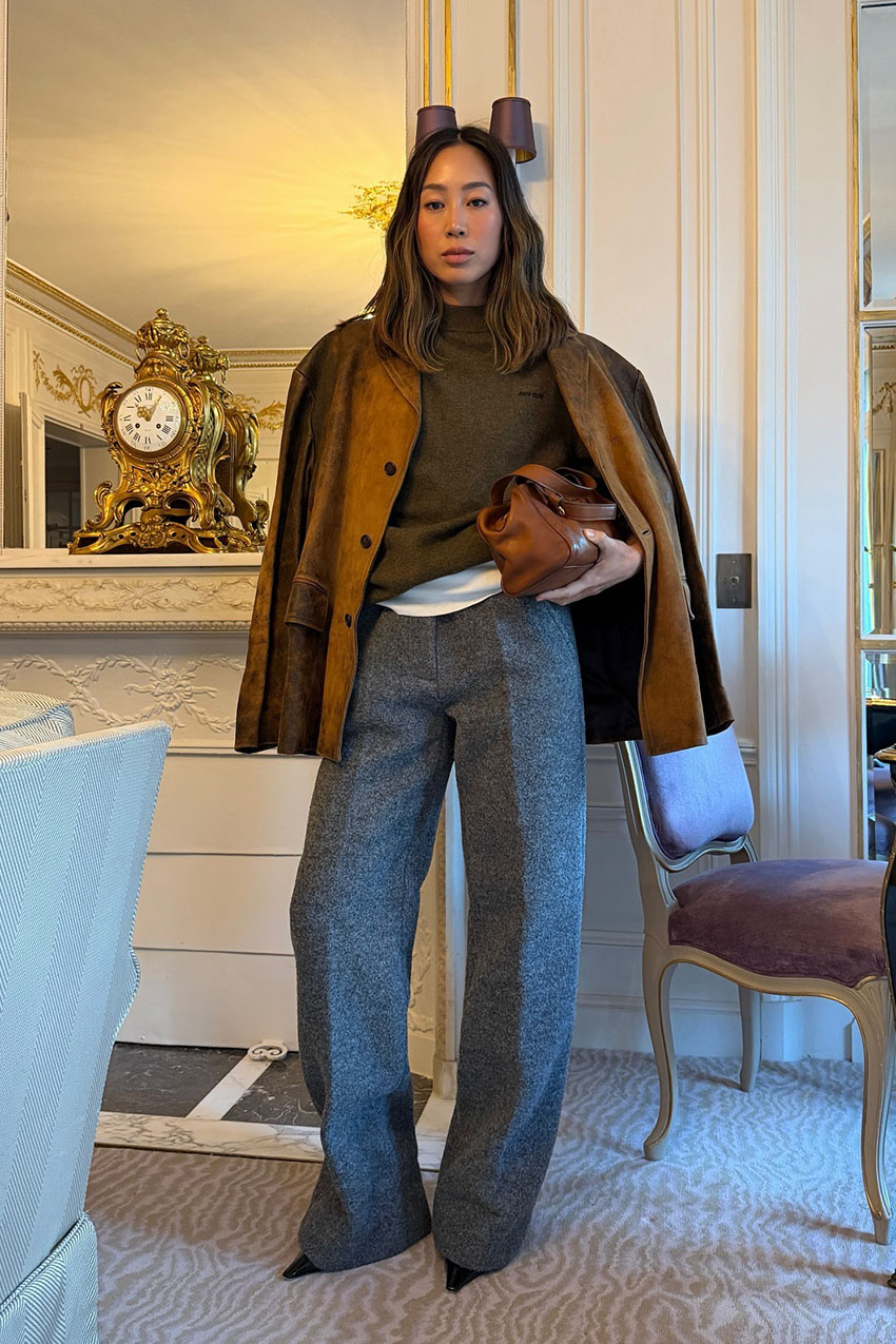 A woman wearing a sweater and gray pants.