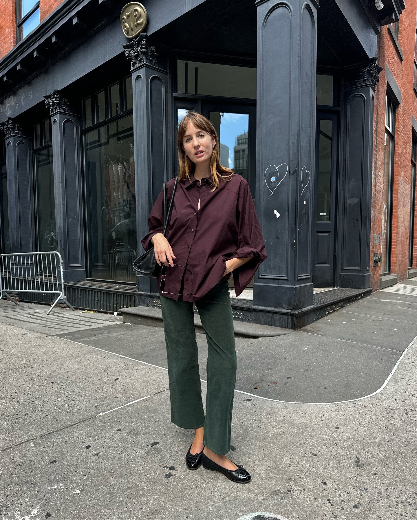 Influencer @lizzyhadfield wears dark green jeans with a burgundy shirt and black ballet flats.
