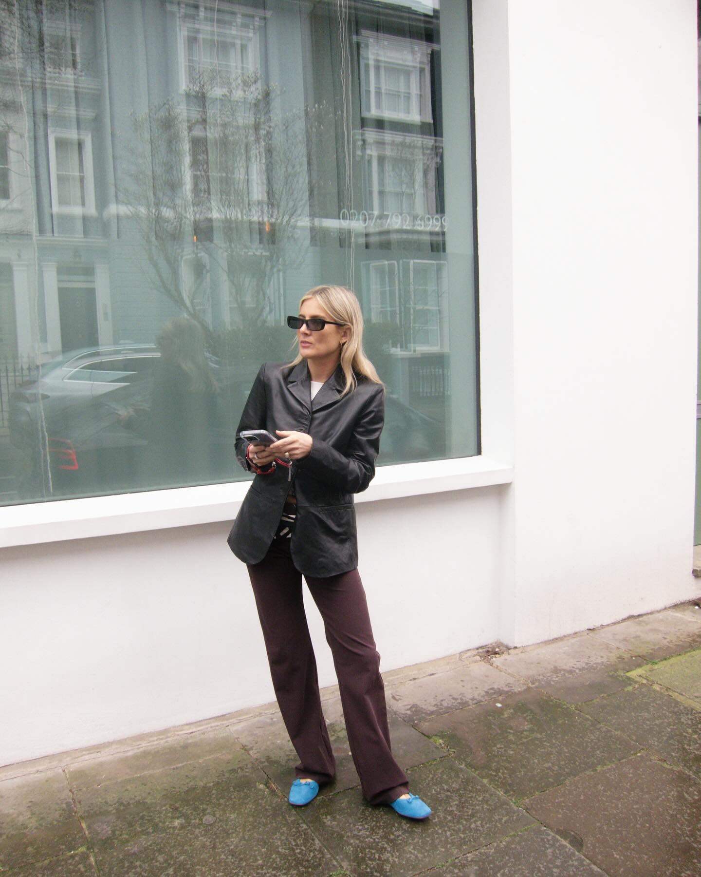 Influencer @lucywilliams02 wears dark brown jeans with a black leather blazer and blue ballet flats.