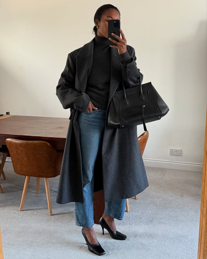 Marilyn wears a black trench coat, turtleneck, straight leg jeans and black heels.