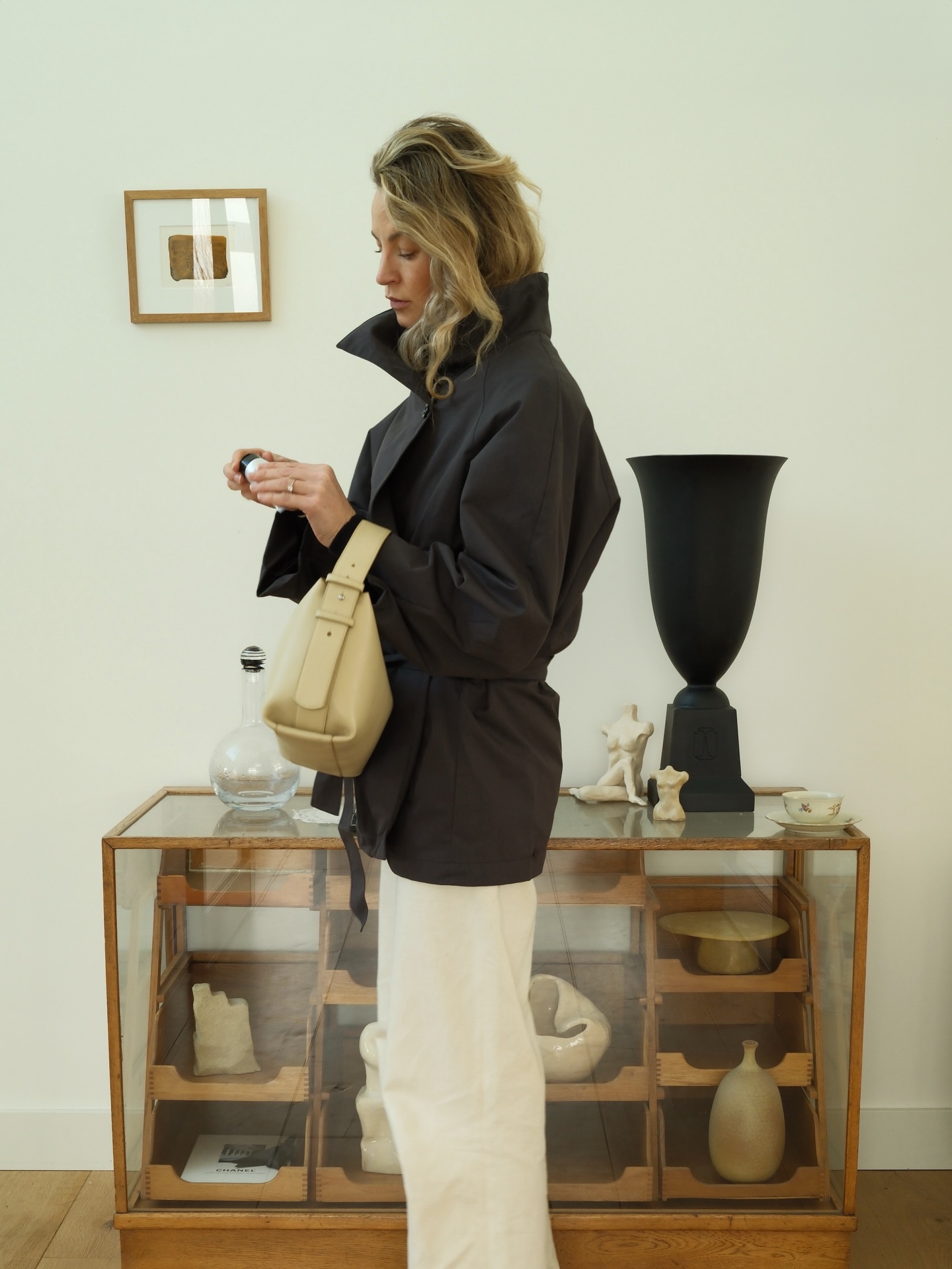 Anouk Vye wears a leather jacket, white trousers and a yellow leather bag.