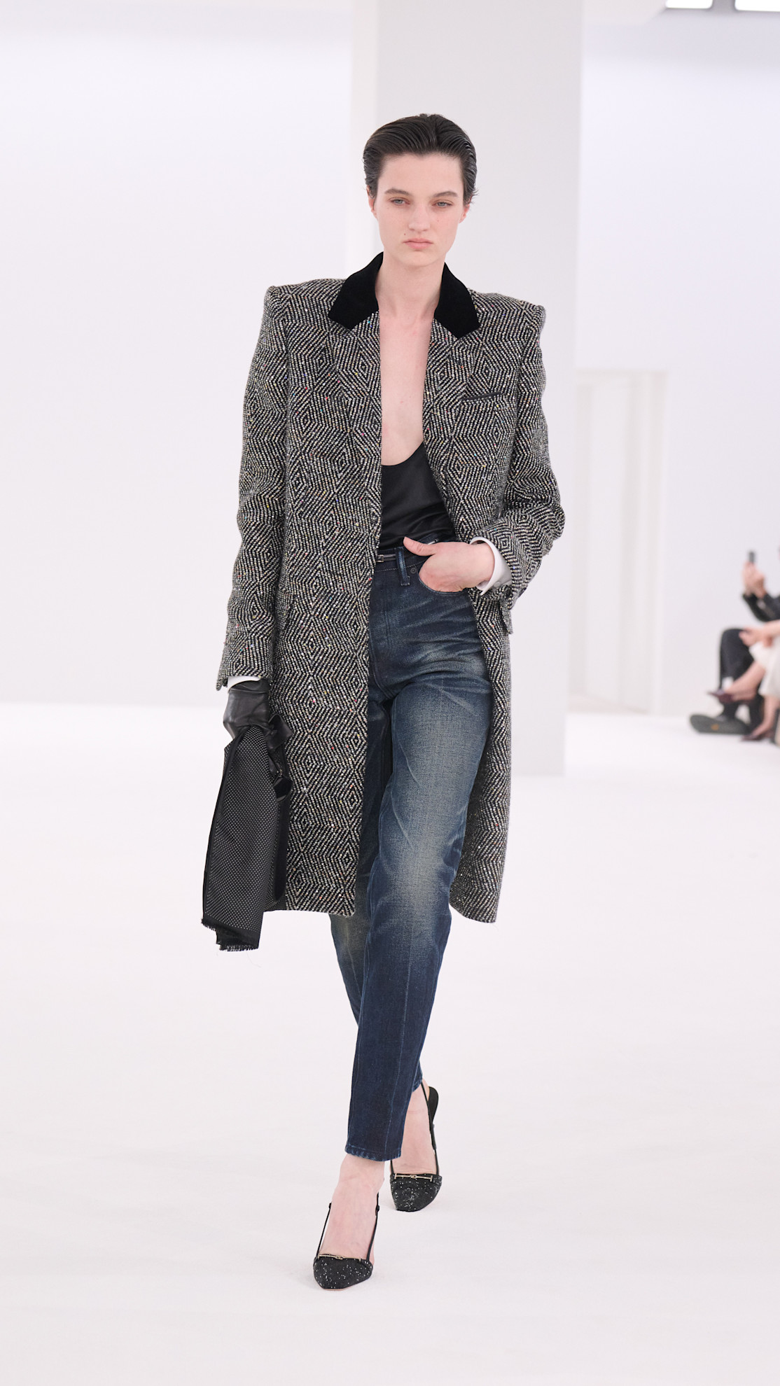 a Tom Ford model wearing a wool coat, black tank top, and denim jeans