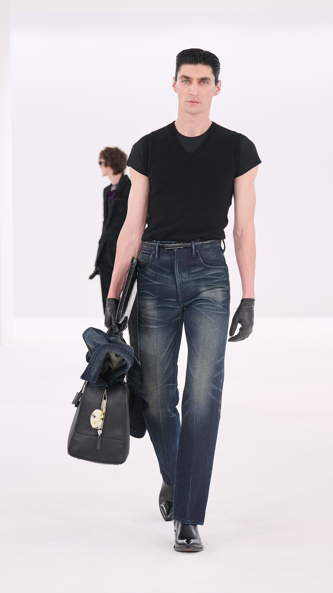 a Tom Ford wearing a black t-shirt, denim jeans, and pointed toe boots