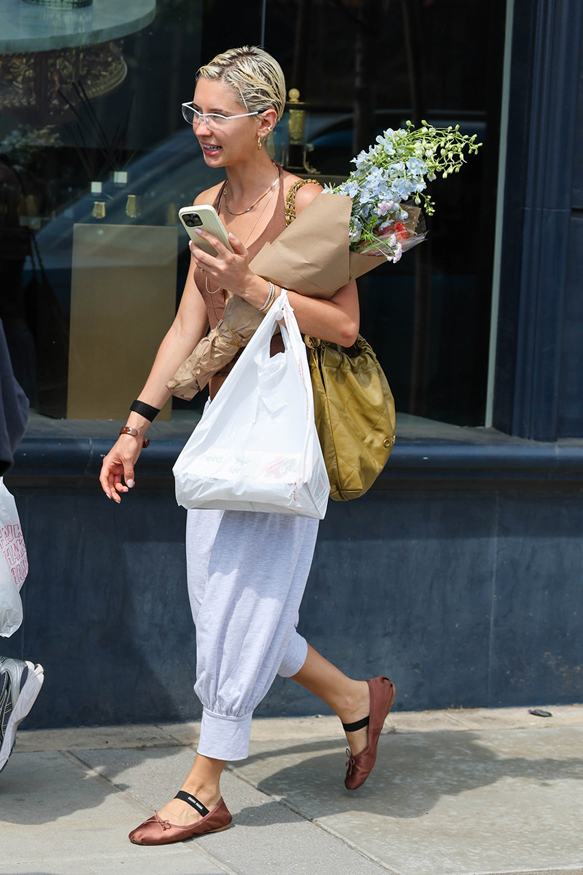 Iris Law wearing a brown tank top, white genie pants, and pink Miu Miu satin flats