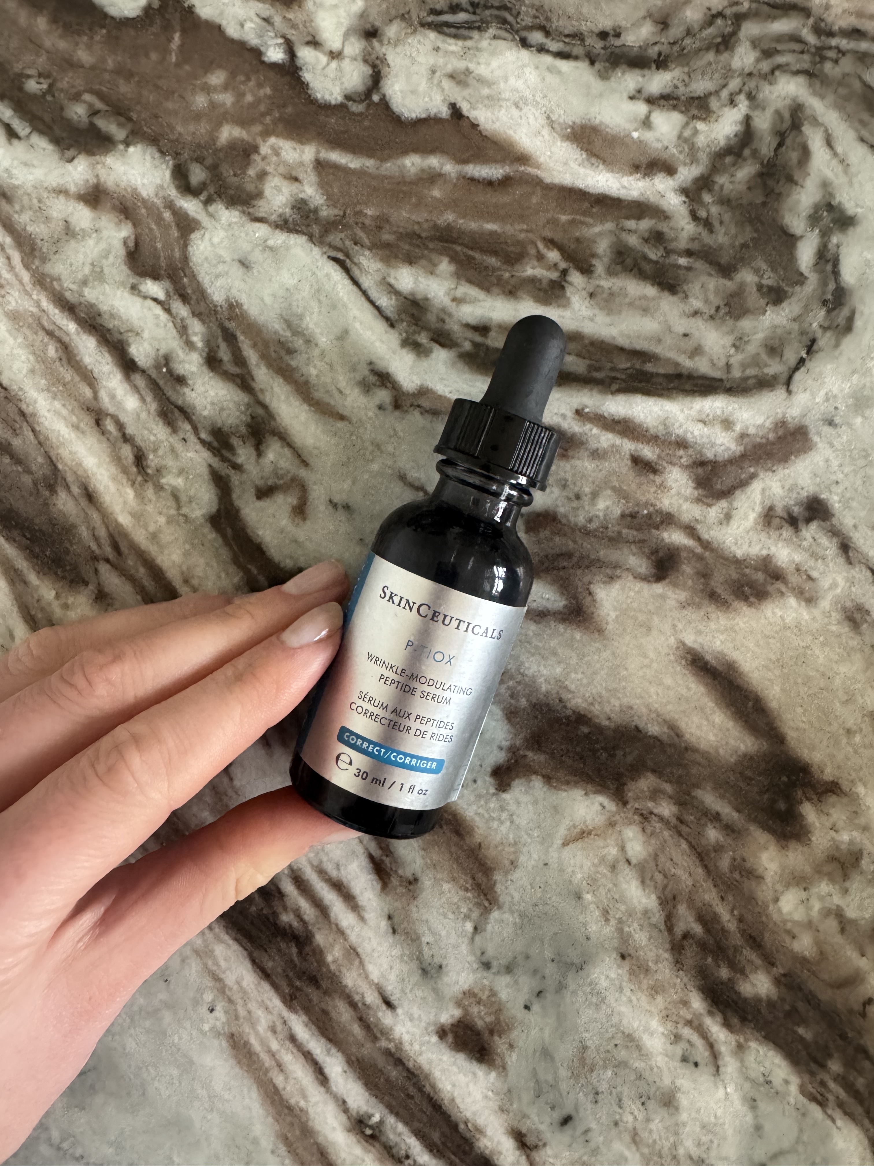 A bottle of Eleanor's SkinCeutical Ptiox serum on a marble table