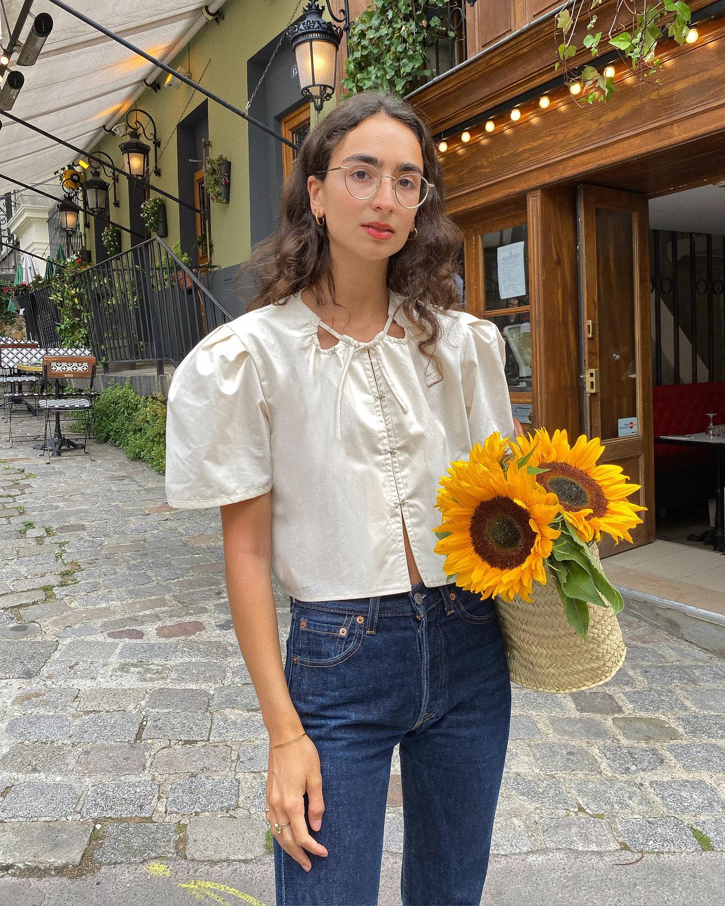 Pia wears a puff sleeve blouse, basket bag and blue straight leg jeans