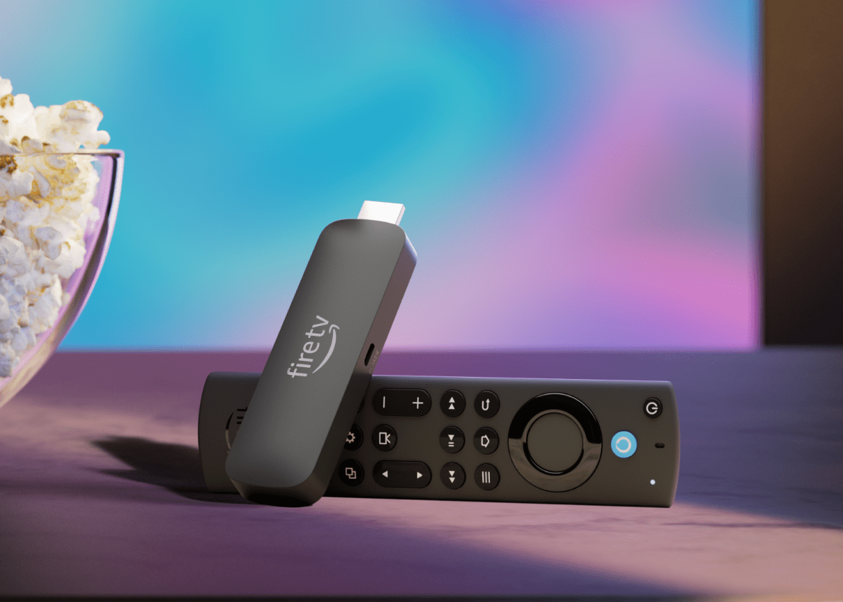 An Amazon Fire TV Stick 4K Max streaming stick with its remote sitting beside a bowl of popcorn in front of a TV.