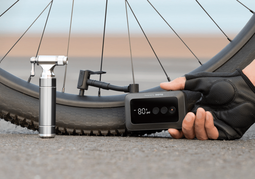 The Hoto Air Pump Pocket being held by a hand and pumping up a bike tire.