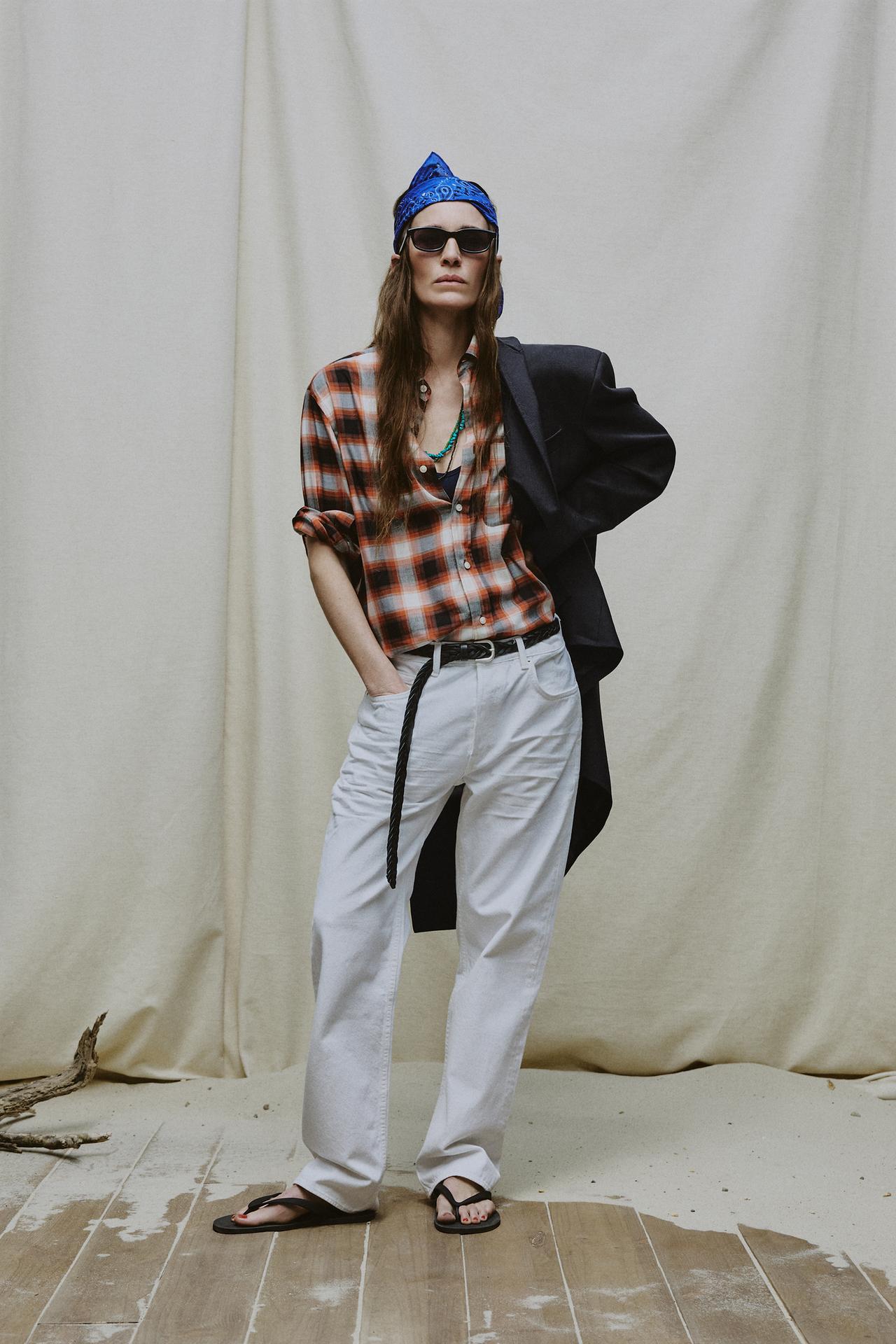 Model wears plaid shirt, white jeans, flip flops, blazer, and blue bandana