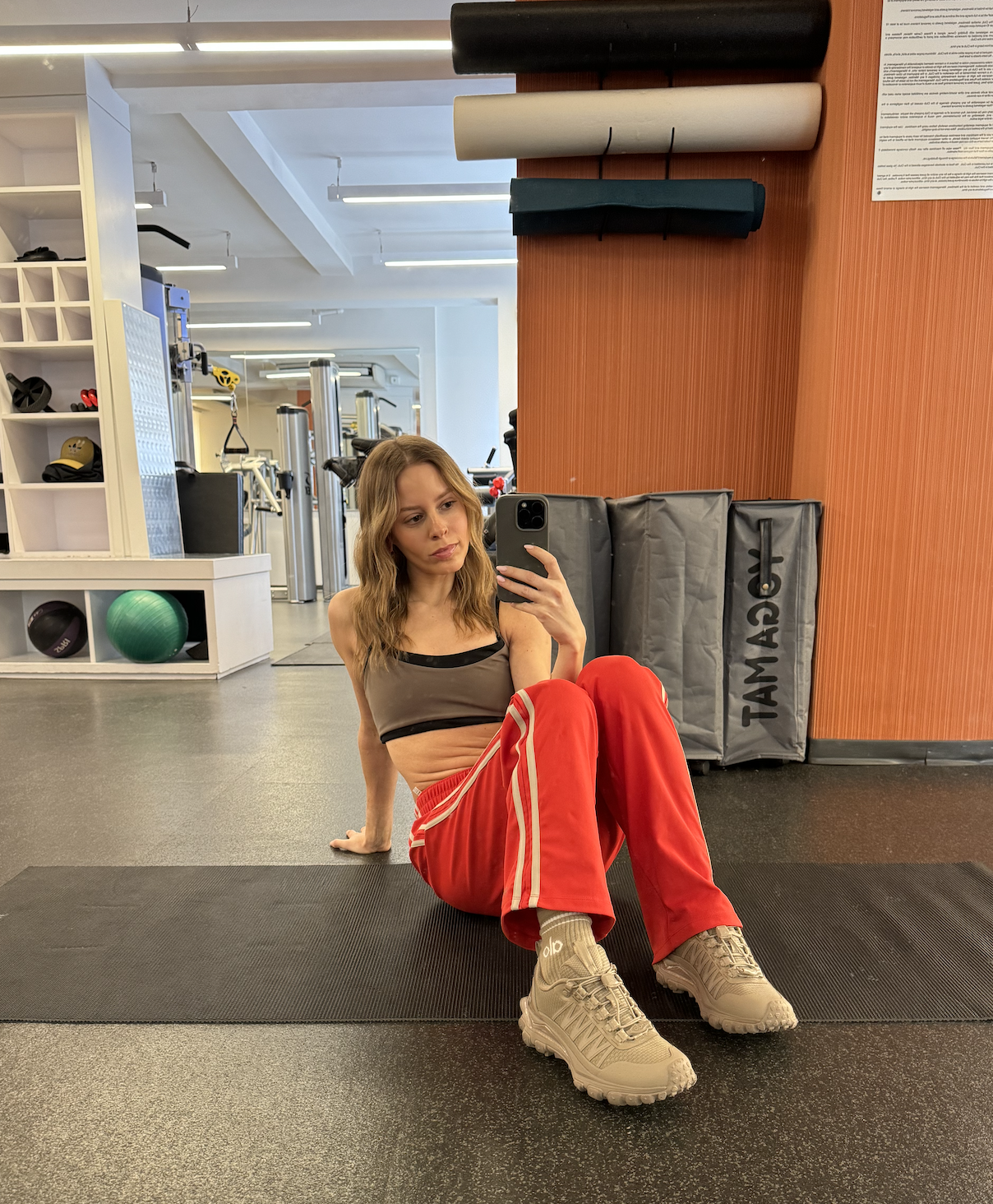 Nikki wears a sport bra, track pants, and alo sneakers.