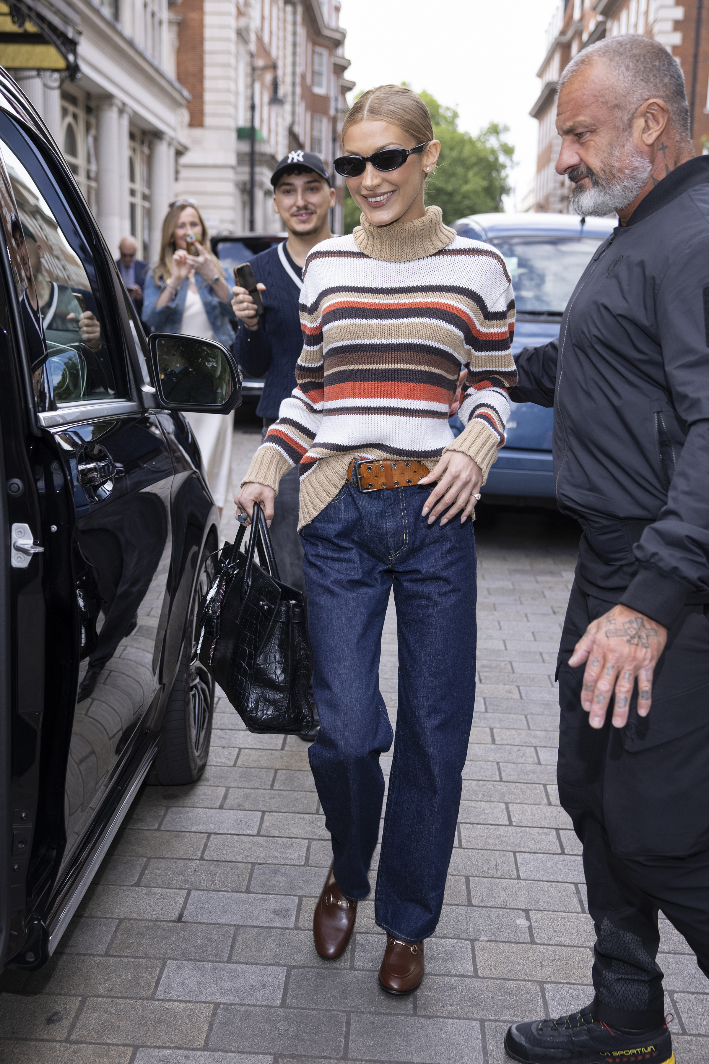 Bella hadid wears a stripe sweater, dark-wash jeans, and loafers.