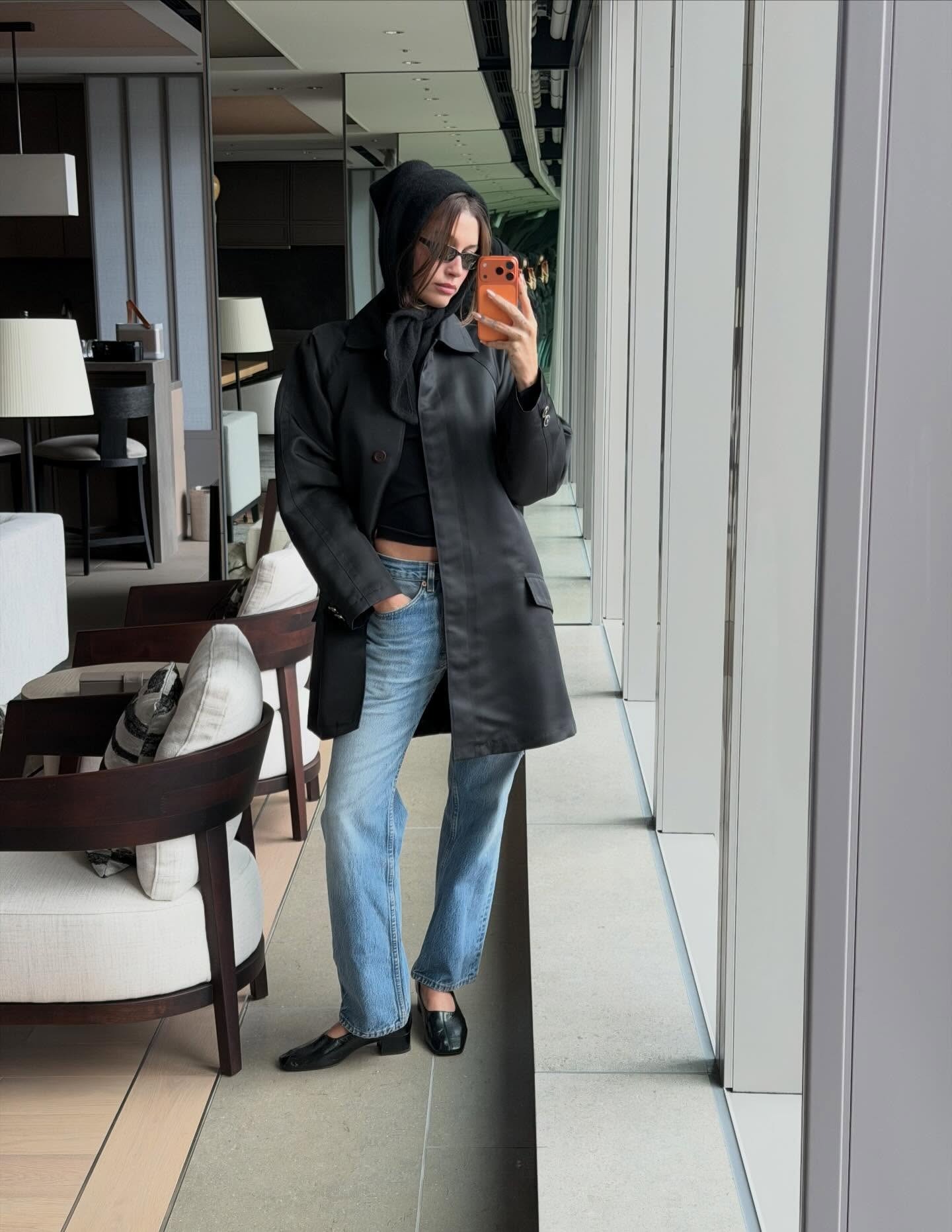 hailey wears a car coat, low-rise jeans, and high-vamp pumps.