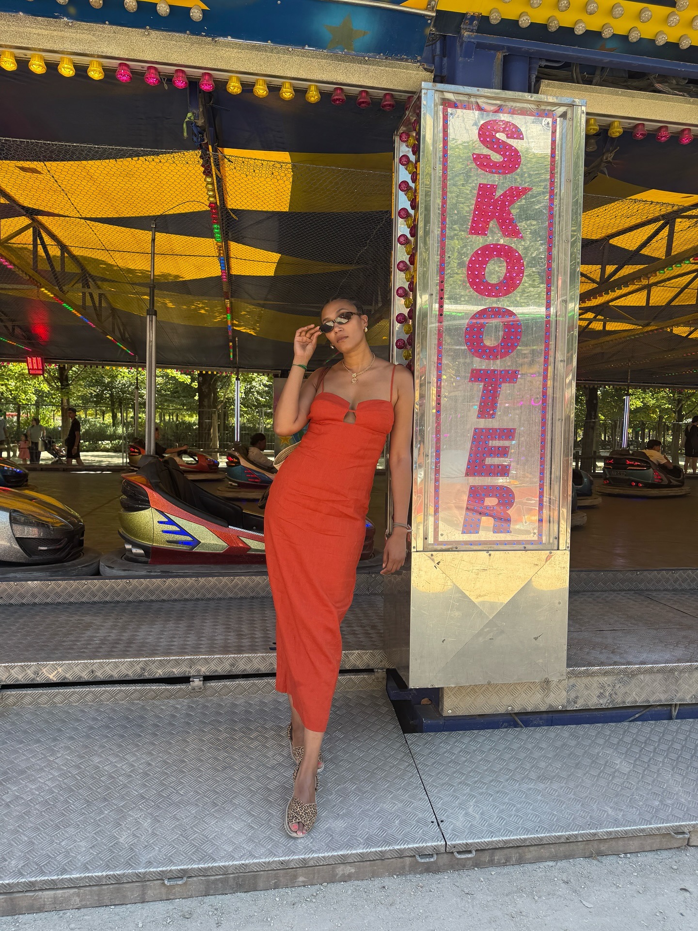 Influencer @lenafarl poses wearing a tomato red dress with beige sandals.