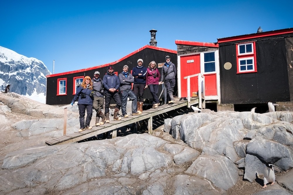 team members on a boardwalk outside a red and black building