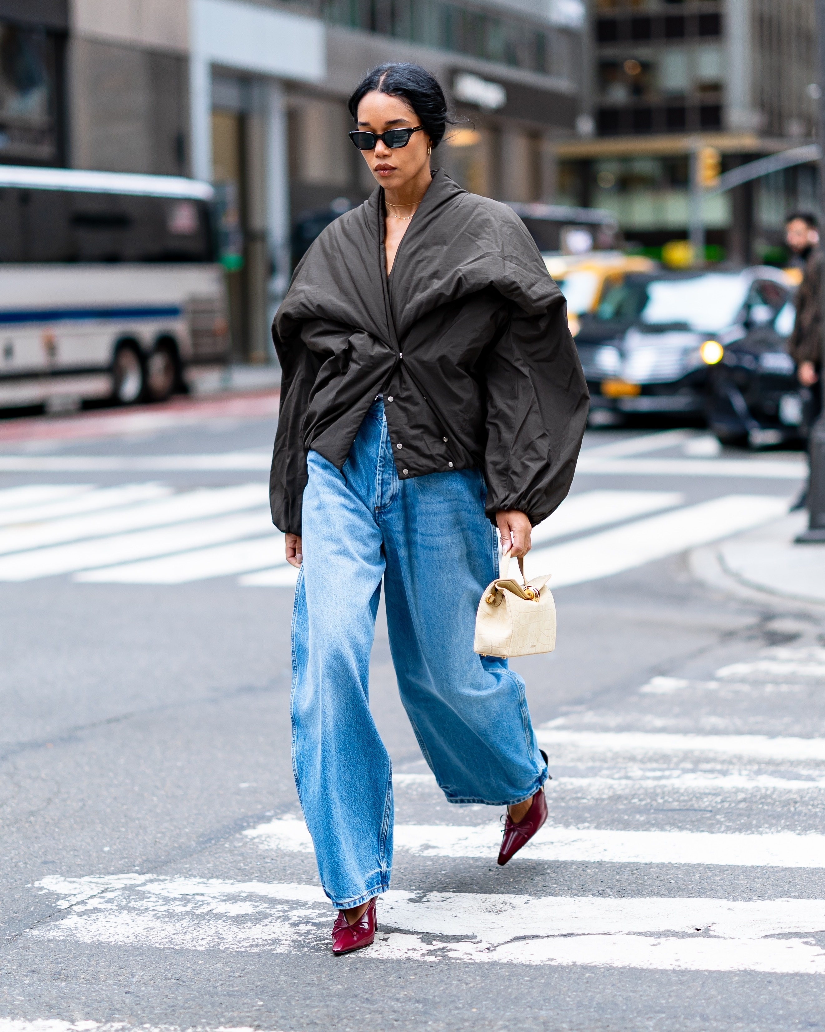 Laura Harrier wearing a puffer jacket, barrel-leg jeans, and burgundy patent leather heels in New York City.