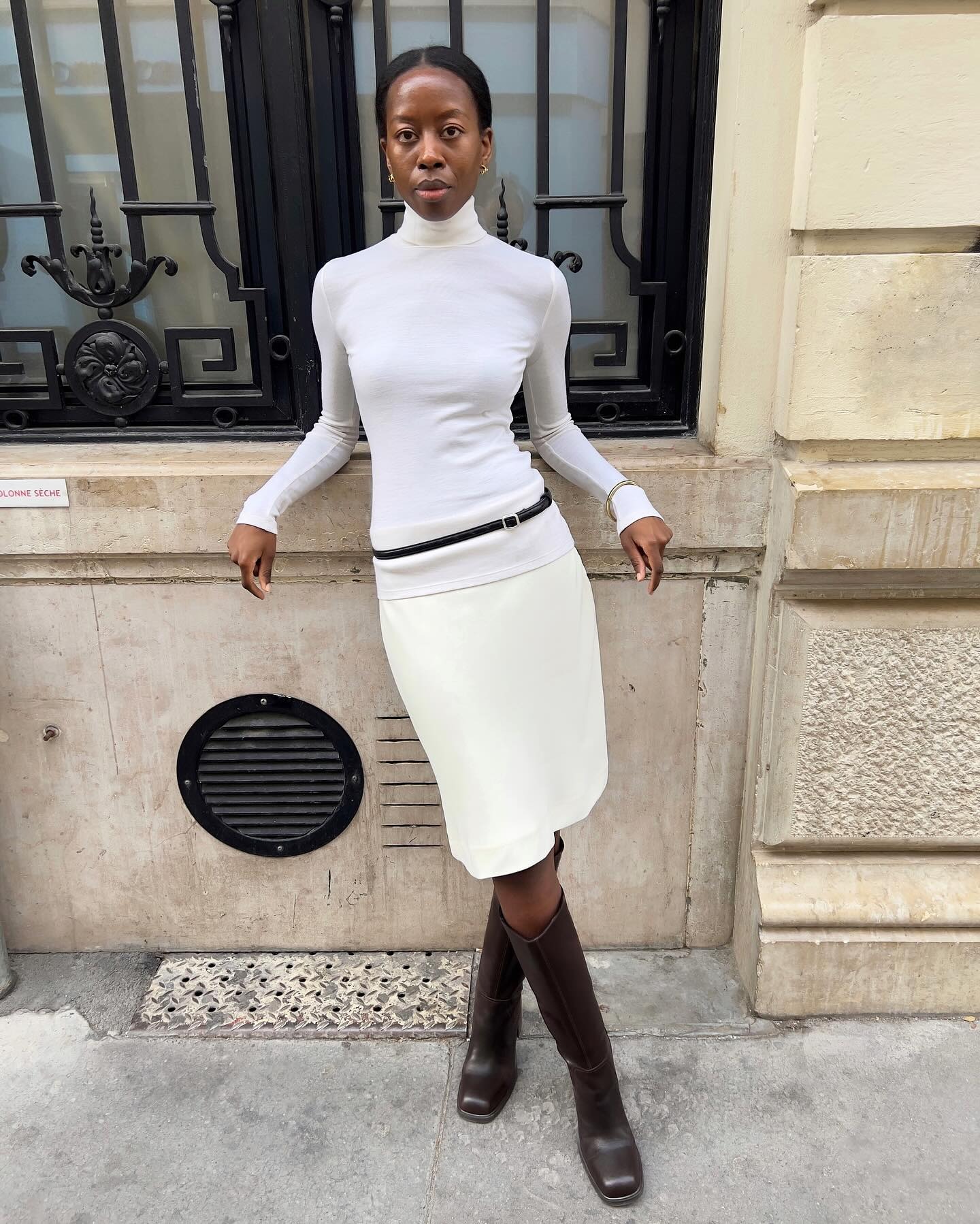 Influencer @sylviemus_ wears a white pencil skirt with a white turtleneck and brown boots.