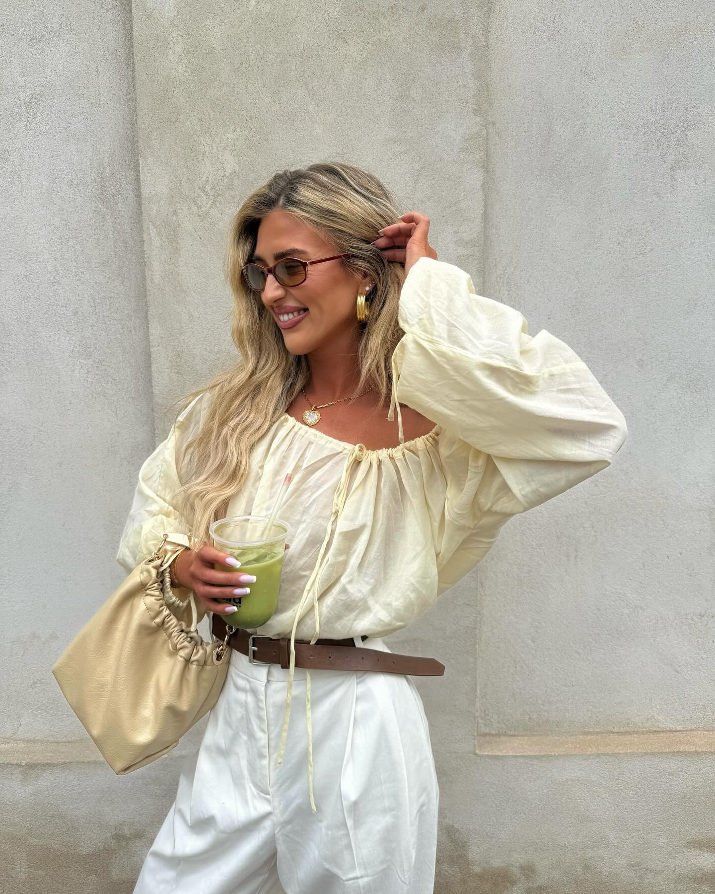 Influencer @emilisindlev wears a yellow blouse with white trousers and a beige bag.