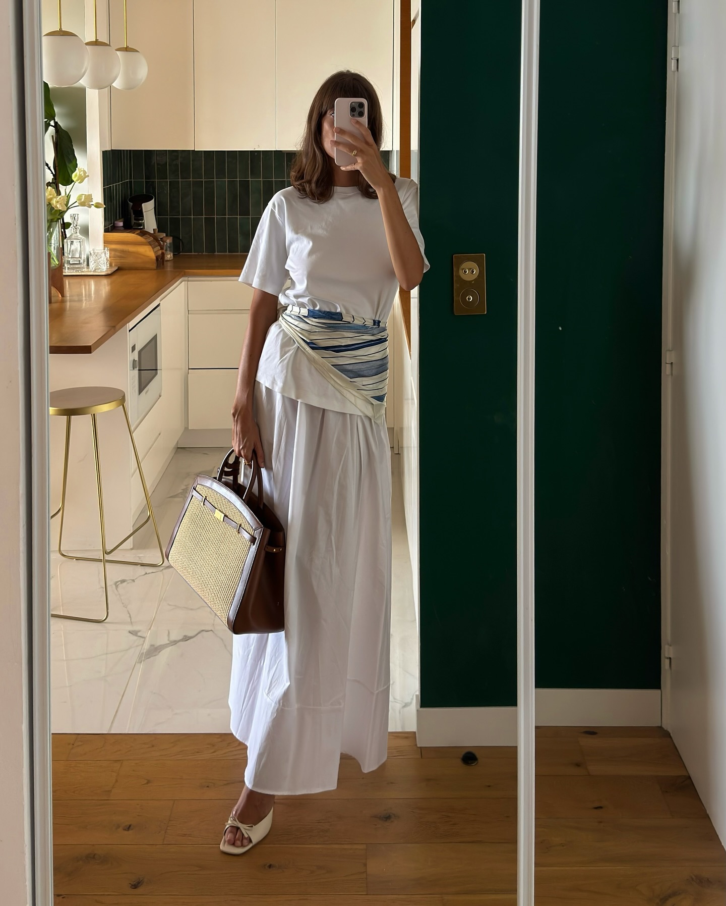 Julie wearing a white t-shirt, white skirts and silk scarf around her waist.