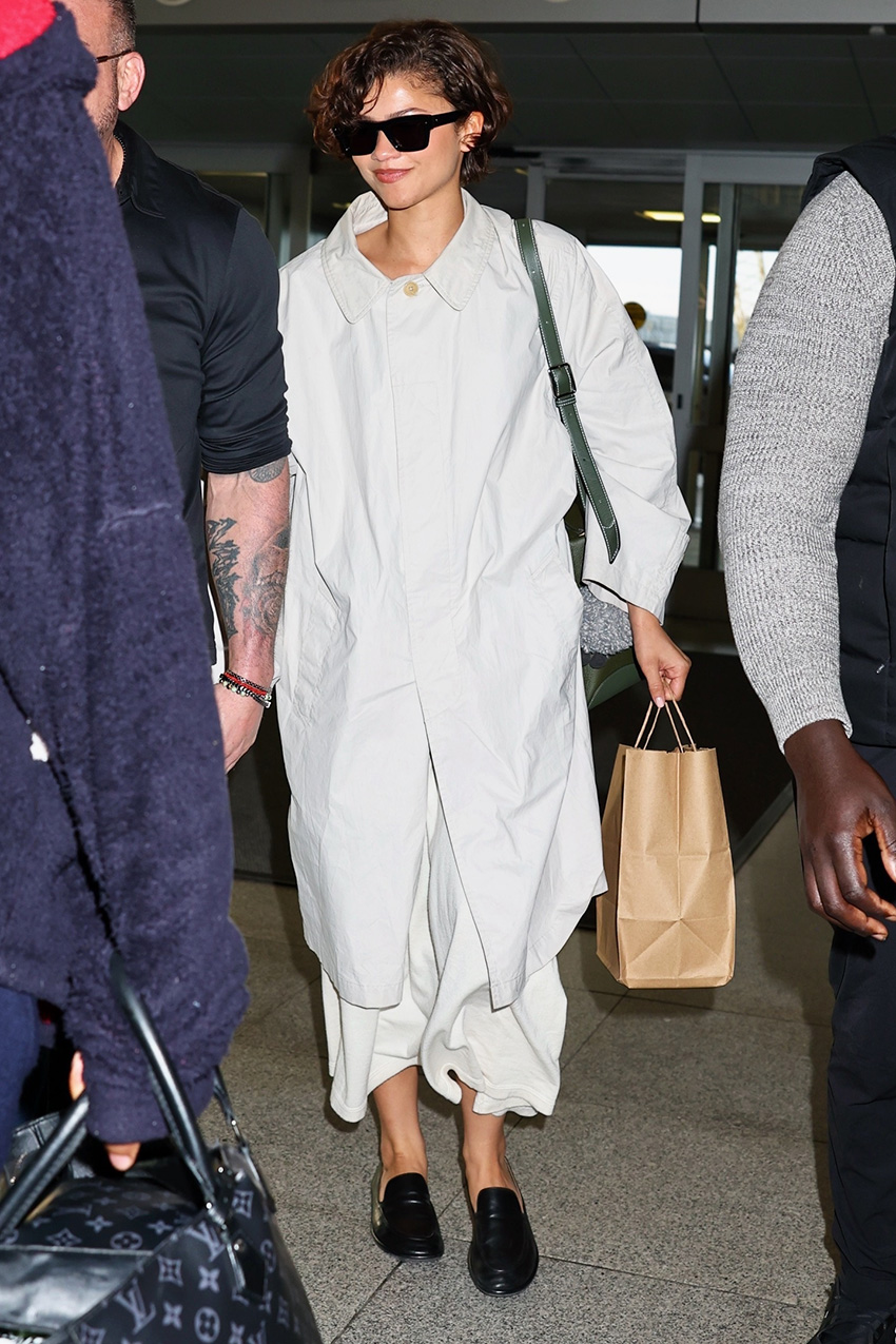 Zendaya wearing a The Row trench, skirt, and loafers at JFK airport