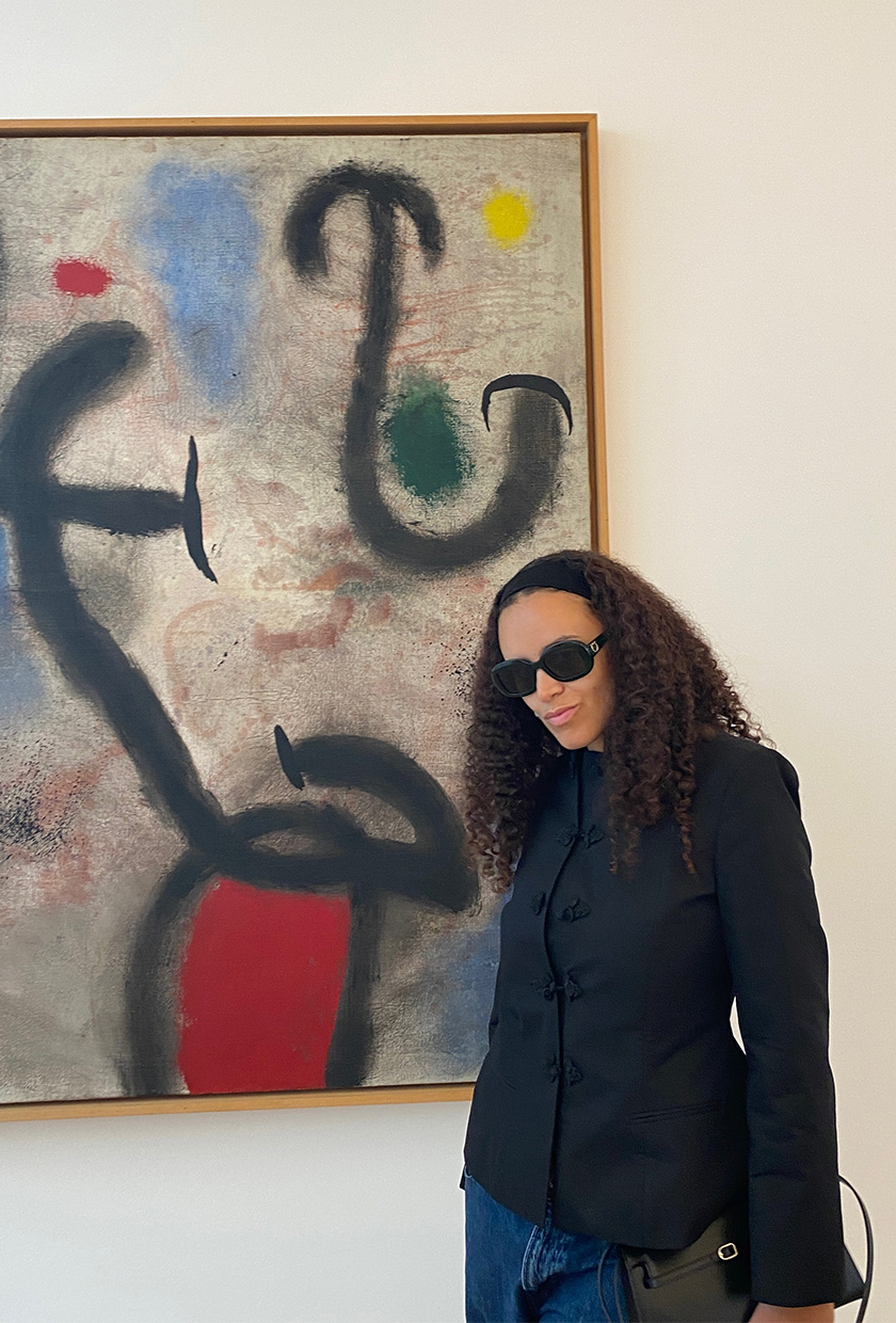 An editor standing in front of a painting at Fondation Maeght wearing a black Zara clasp blazer styled with jeans.