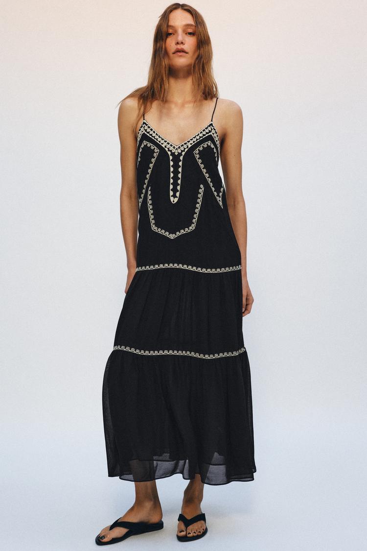 Model wears black dress and flip flops.