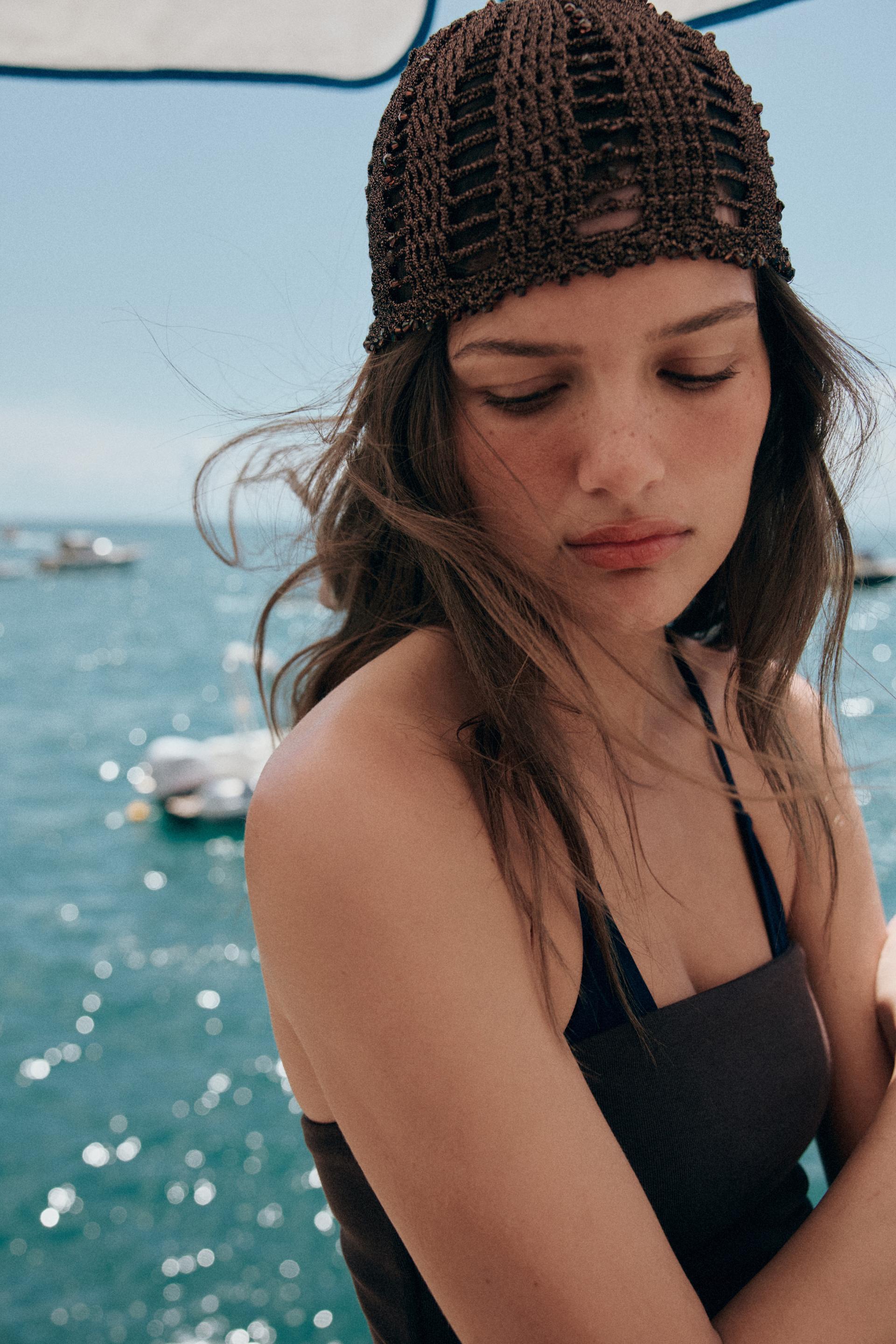 Woman wears dark brown crocheted skullcap.