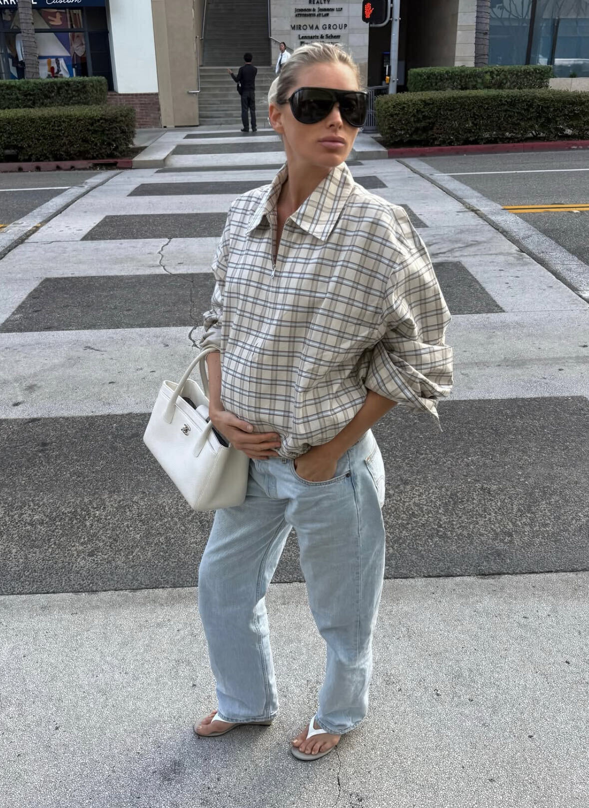 elsa wears a plaid top, low-rise baggy jeans, and white flip-flops.