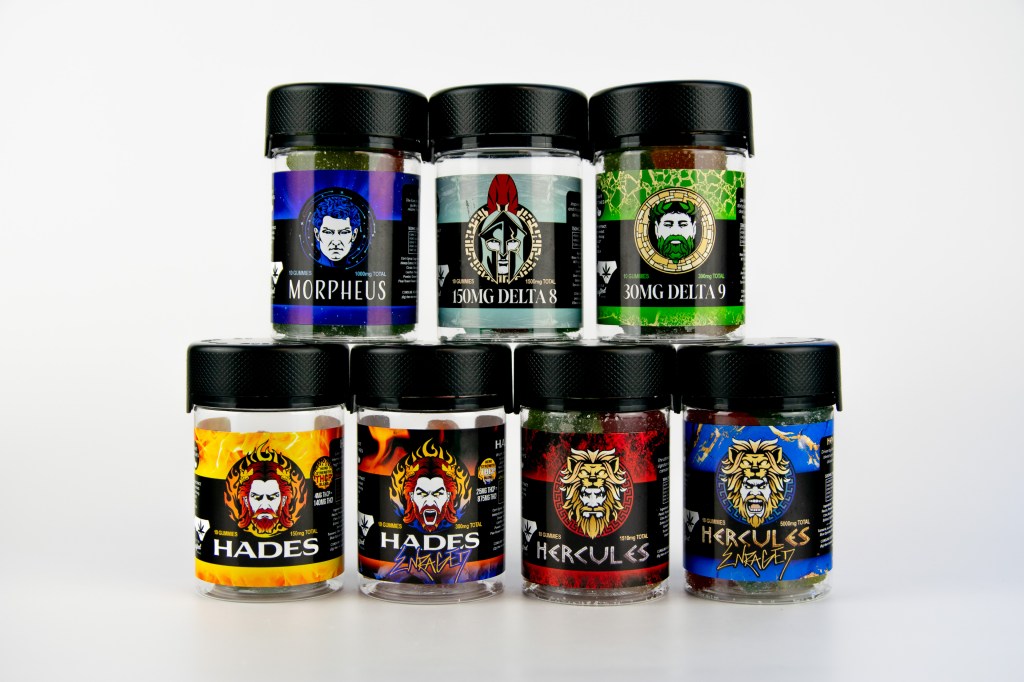 Assortment of supplement containers featuring various Greek mythological figures and branding, including Morpheus, 50mg Delta 8, 30mg Delta 9, Hades, and Hercules.