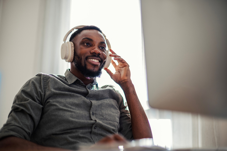 Smiling man wearing headphones working remotely at home