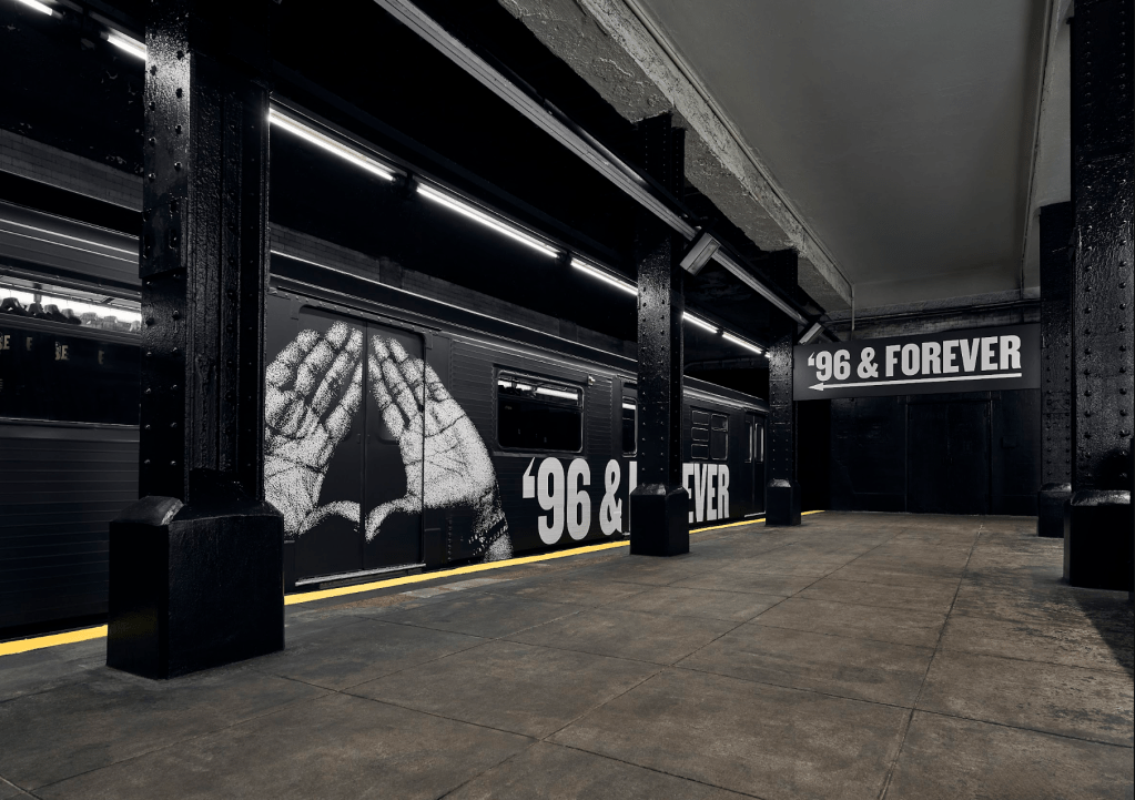 A dark, industrial-style interior space with concrete floors and columns. The walls feature large text that reads "96 & FOREVER" and a large graphic of a spider web.