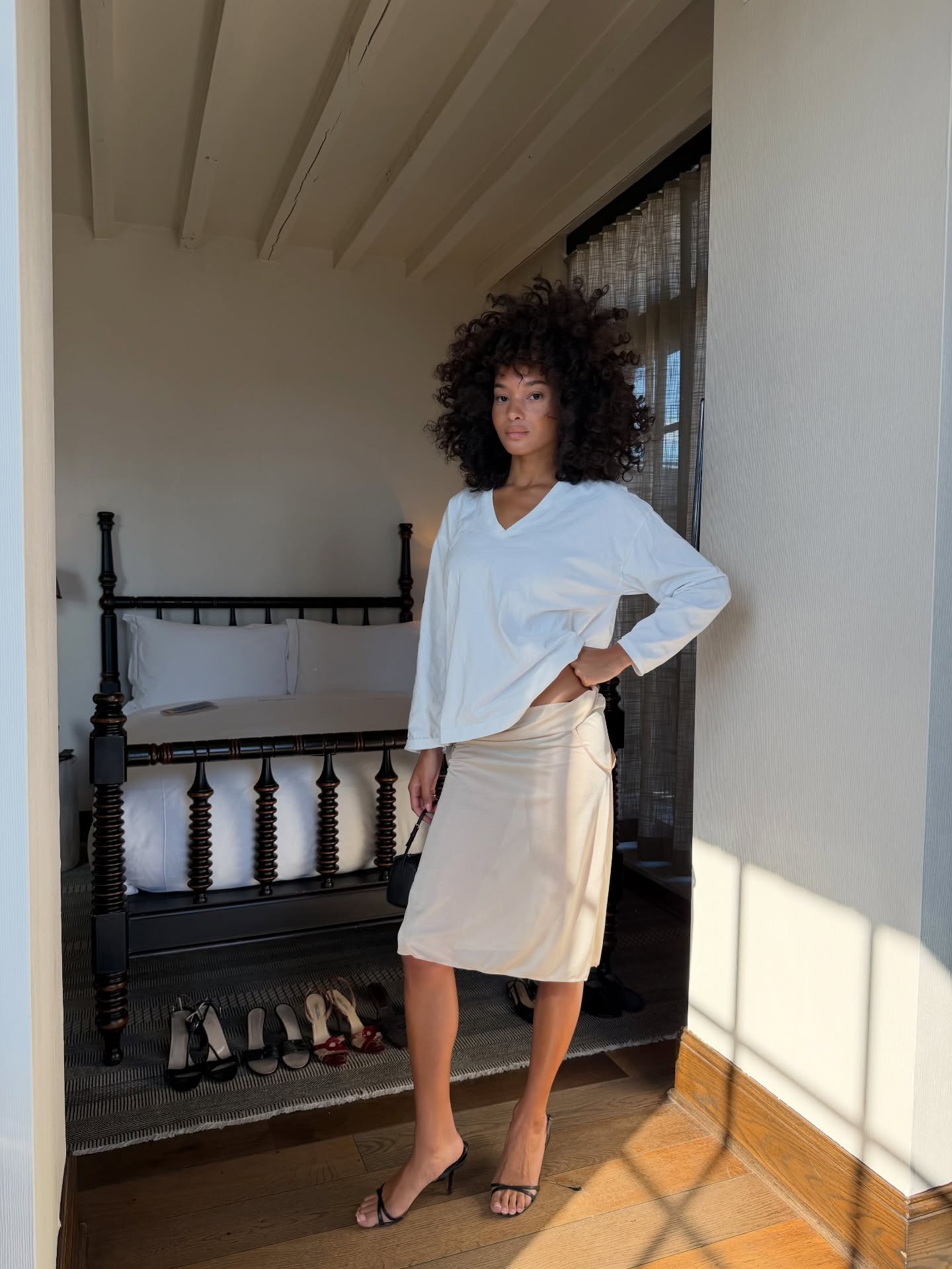 @jamealynee wearing a white T-shirt, knee-length skirt, and strappy sandals.