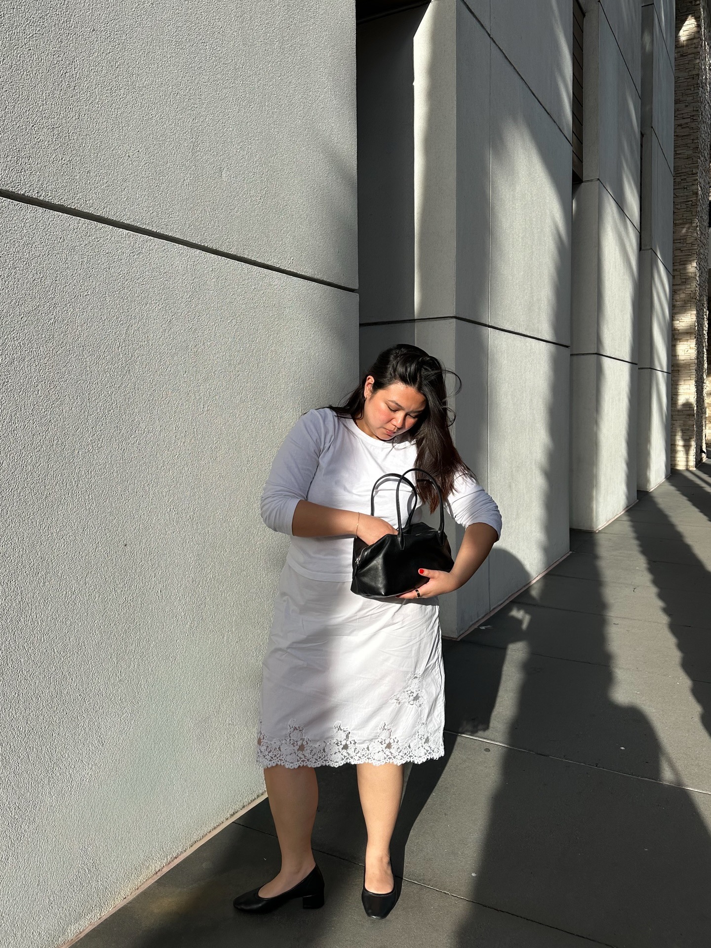 @marina_torres wearing a white T-shirt and lace-trim knee-length skirt with flats.