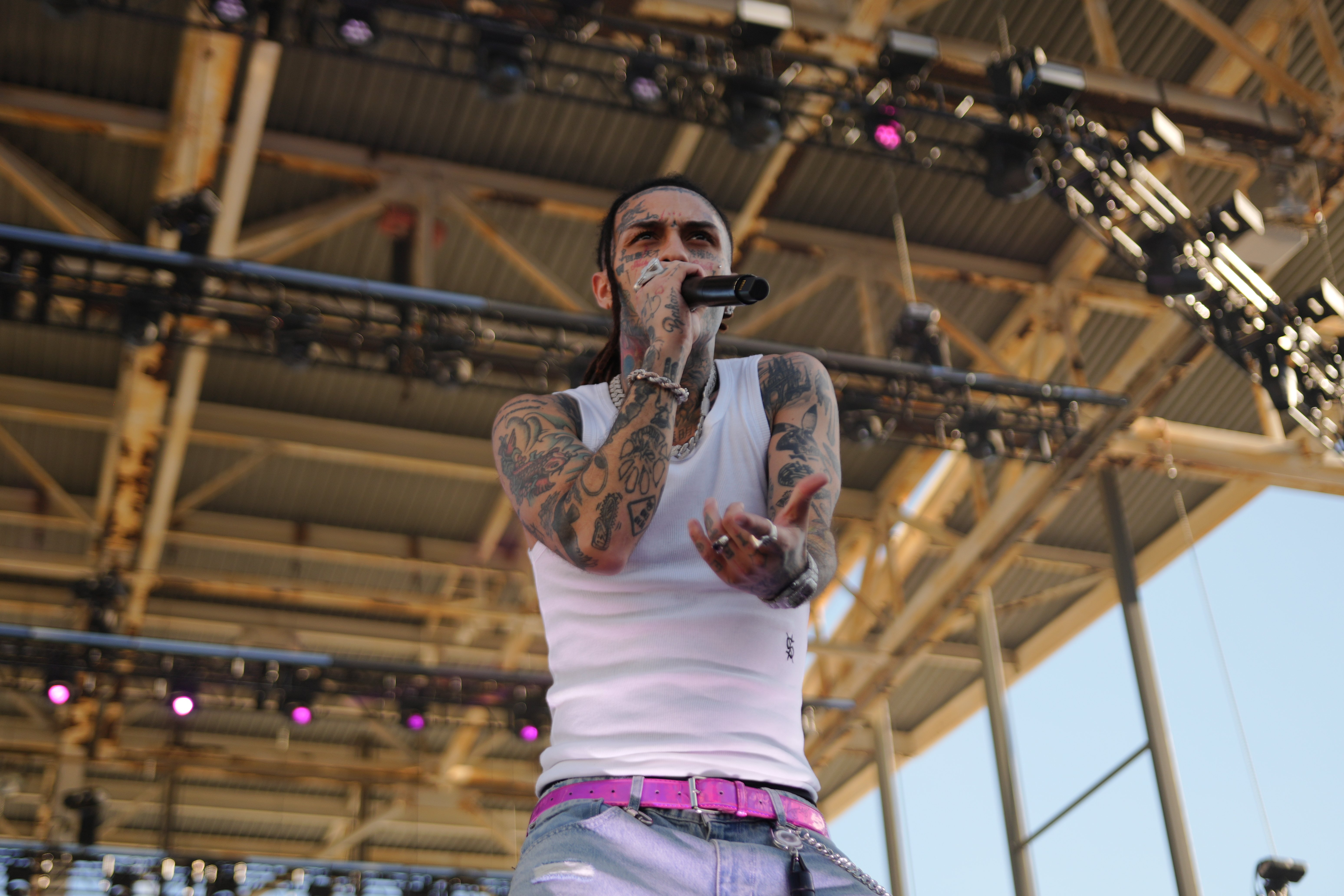 A tattooed man performing on stage, holding a microphone and singing into it.