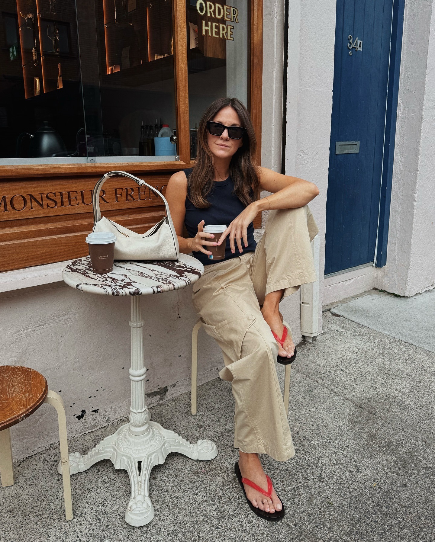 Kim wearing beige trousers, black top and red flip-flops